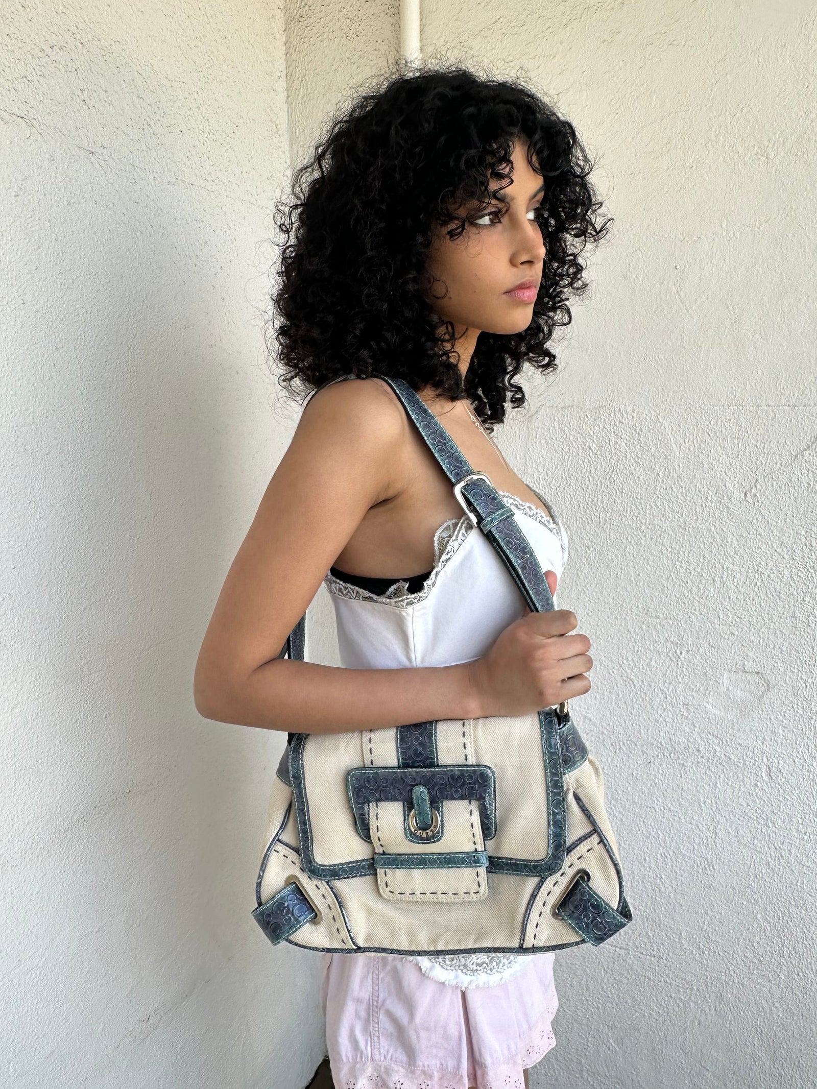 Woman wearing a Y2K 00s Guess cream and blue shoulder bag