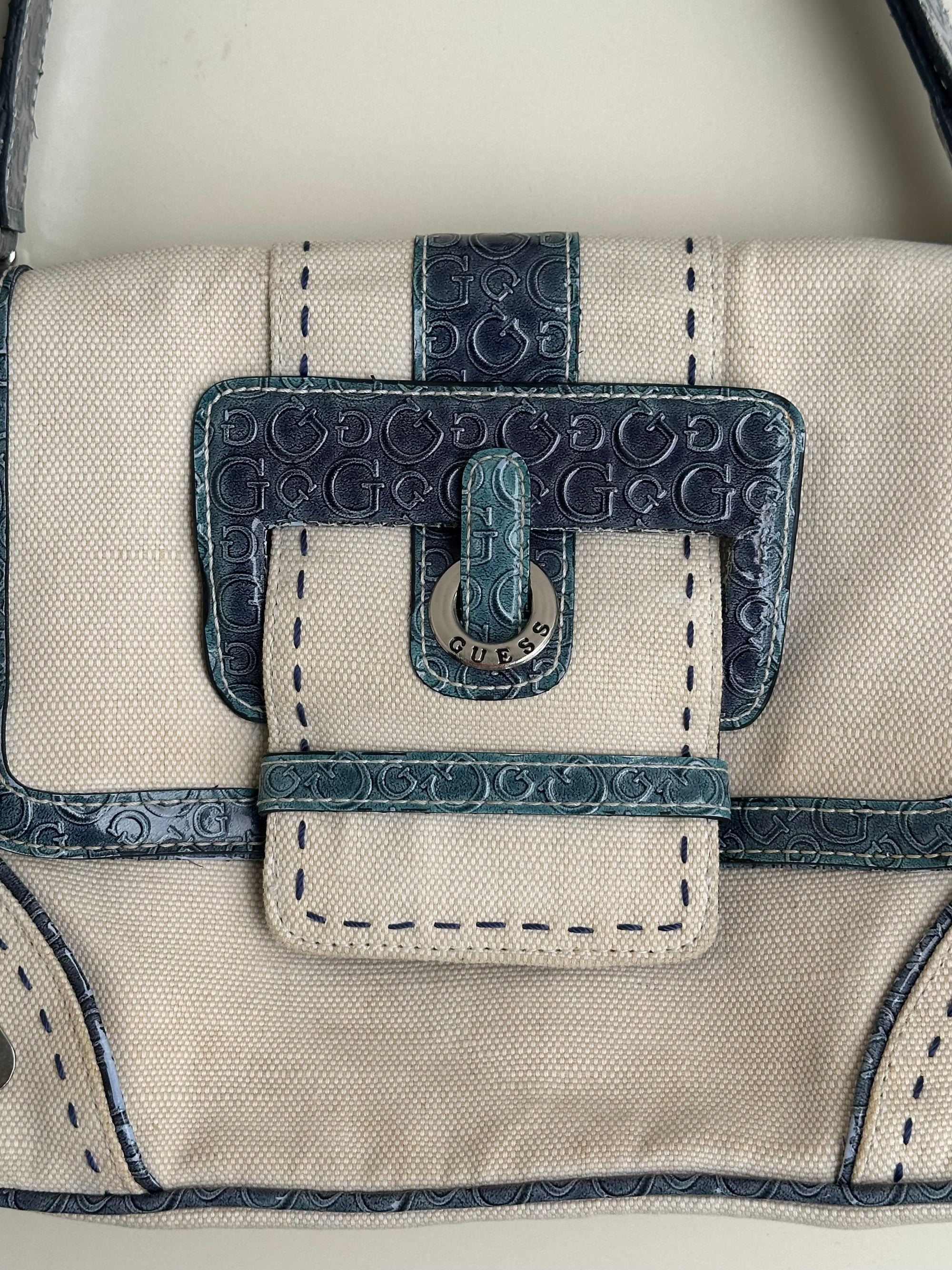 Woman wearing a Y2K 00s Guess cream and blue shoulder bag
