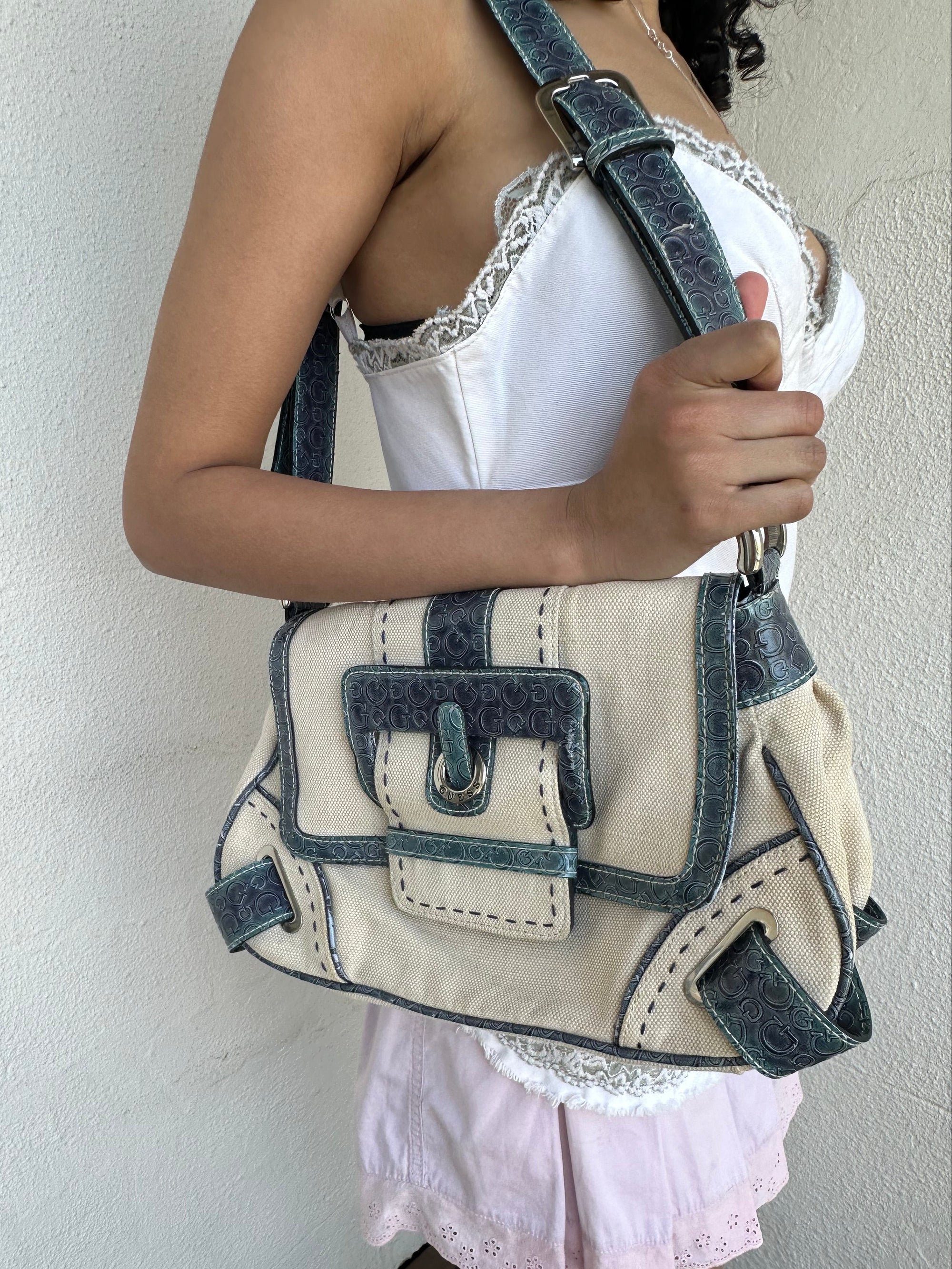 Woman wearing a Y2K 00s Guess cream and blue shoulder bag