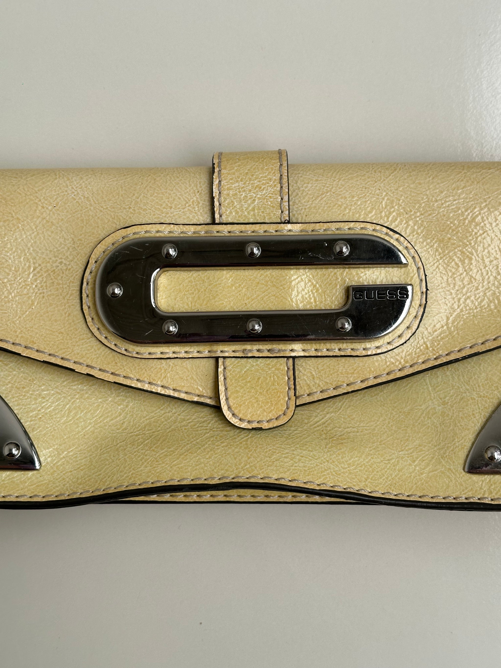 guess-pastel-yellow-mini-shoulder-bagWomen wearing a 00s Y2K Guess pastel yellow mini shoulder bag from the 2000s crafted from faux leather in a small rectangular shape.