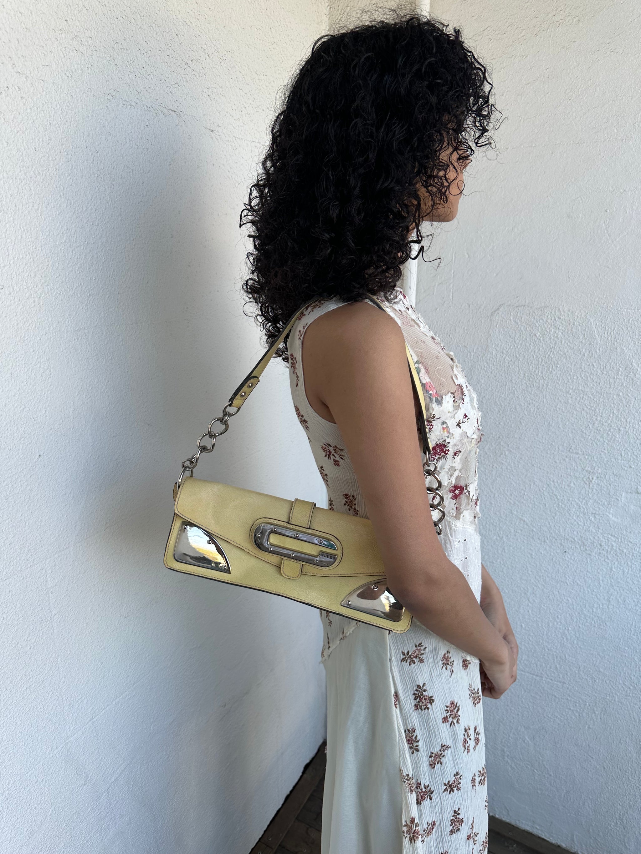 Women wearing a 00s Y2K Guess pastel yellow mini shoulder bag from the 2000s crafted from faux leather in a small rectangular shape.