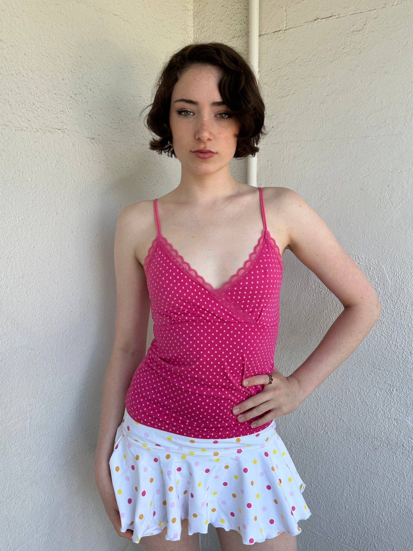 Woman Dressed in Y2K Hot pink and baby pink polkadot cami top featuring small white polkadots throughout a vibrant hot pink base.