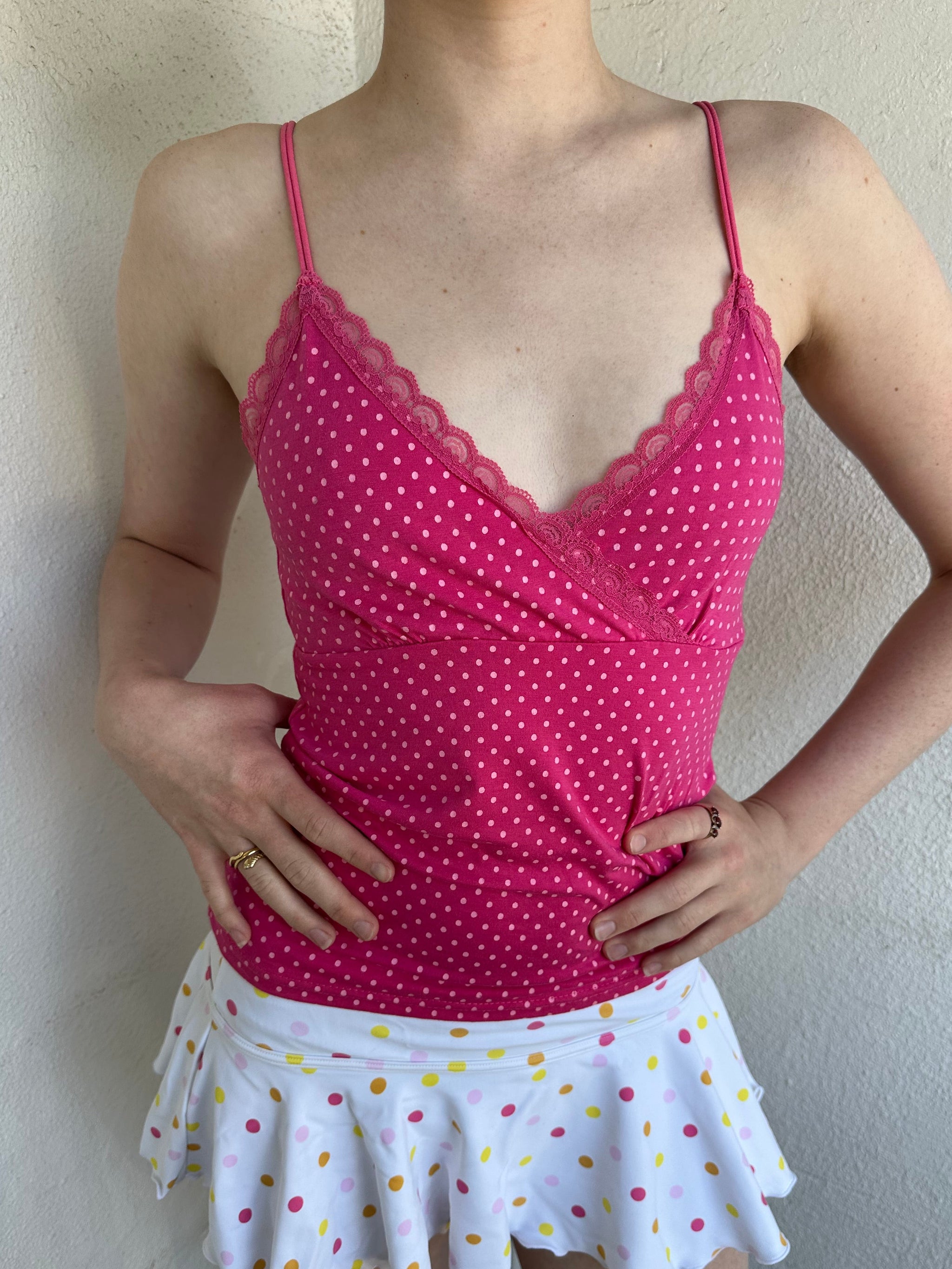 Woman Dressed in Y2K Hot pink and baby pink polkadot cami top featuring small white polkadots throughout a vibrant hot pink base.