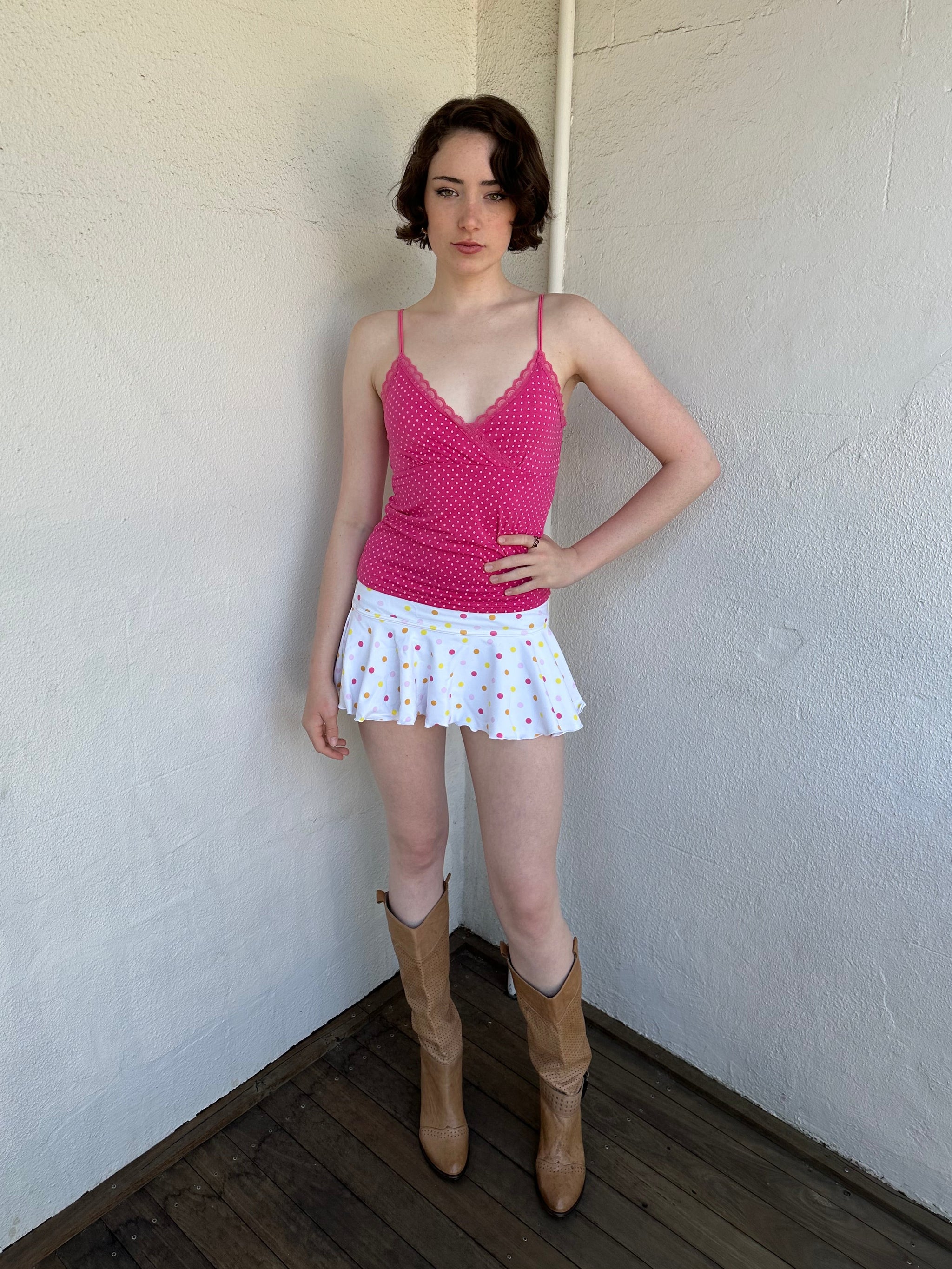 Woman Dressed in Y2K Hot pink and baby pink polkadot cami top featuring small white polkadots throughout a vibrant hot pink base.