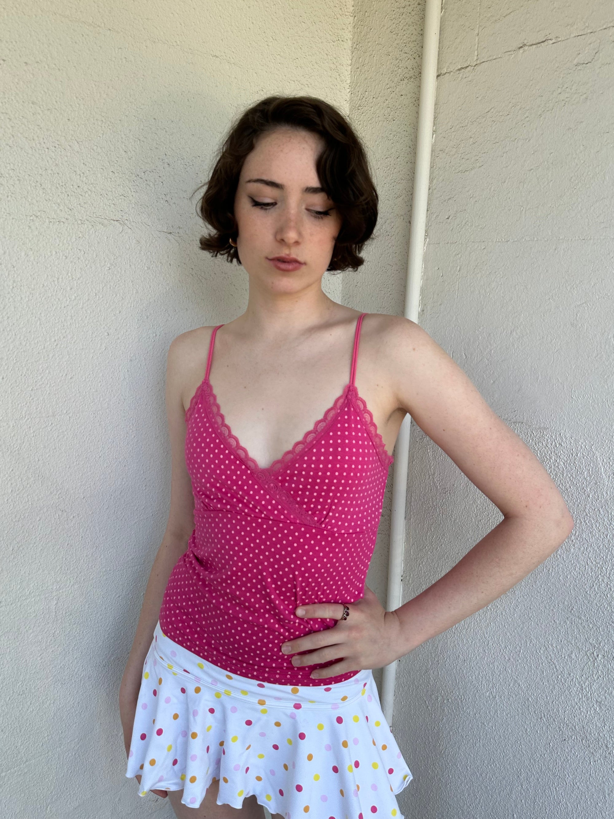Woman Dressed in Y2K Hot pink and baby pink polkadot cami top featuring small white polkadots throughout a vibrant hot pink base.