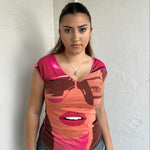 Woman Dressed in Y2K 00s Hot pink graphic t-shirt featuring an illustrated face graphic