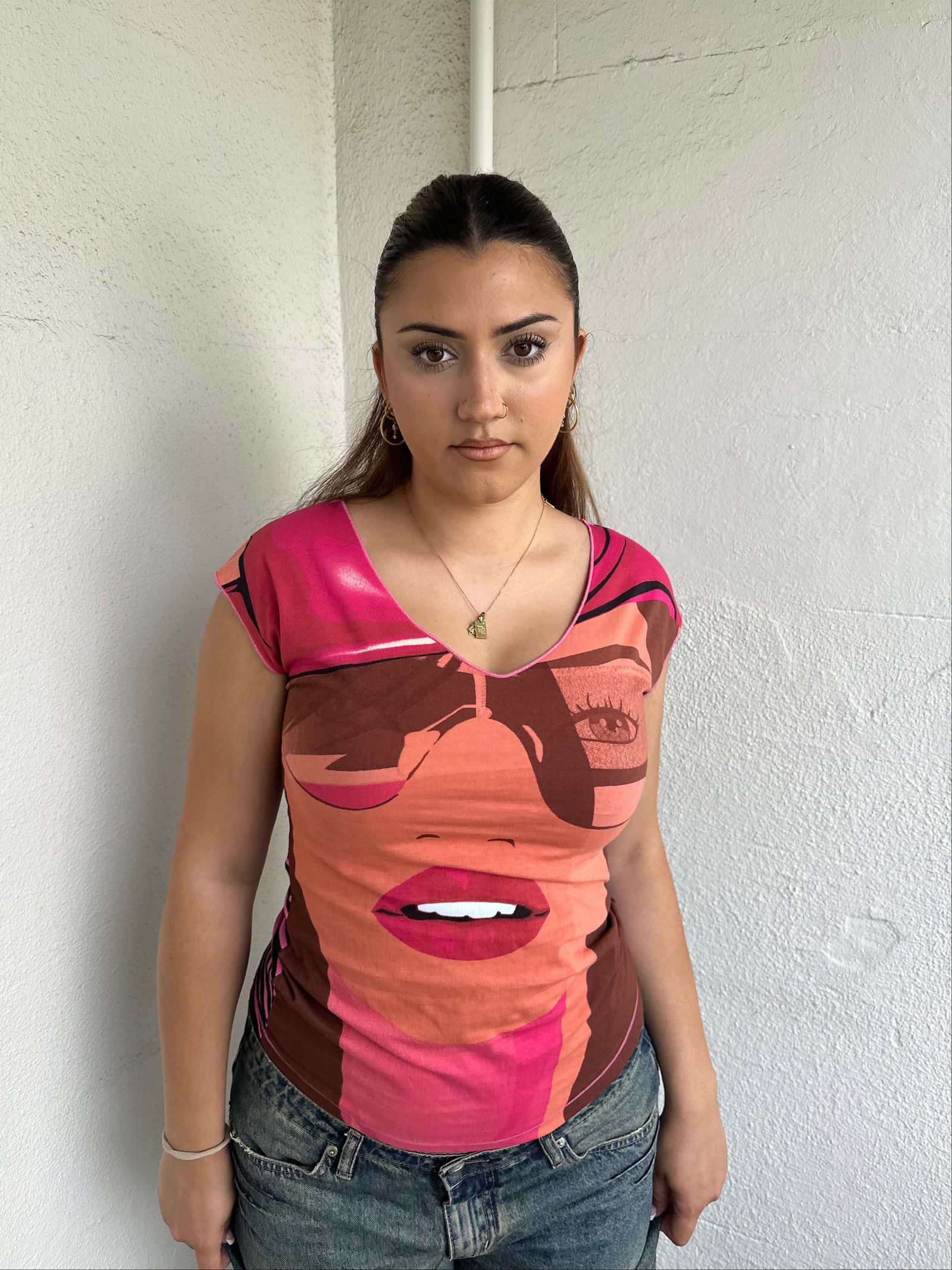 Woman Dressed in Y2K 00s Hot pink graphic t-shirt featuring an illustrated face graphic