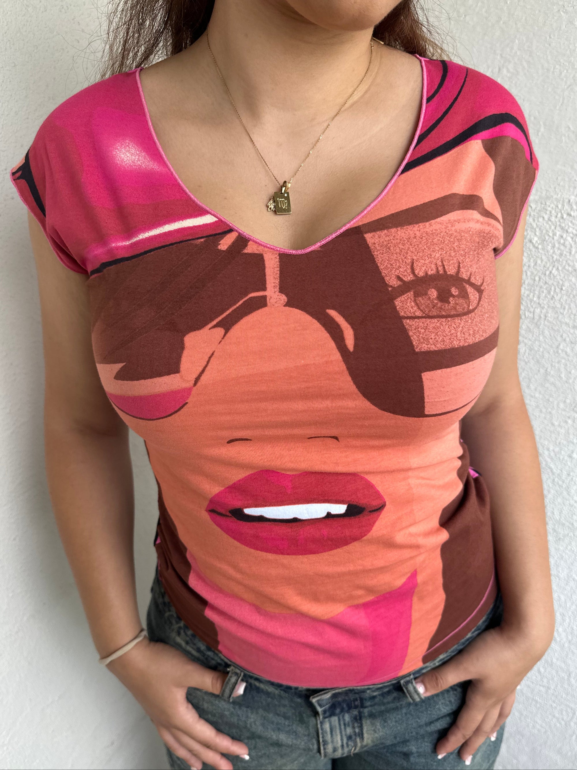 Woman Dressed in Y2K 00s Hot pink graphic t-shirt featuring an illustrated face graphic
