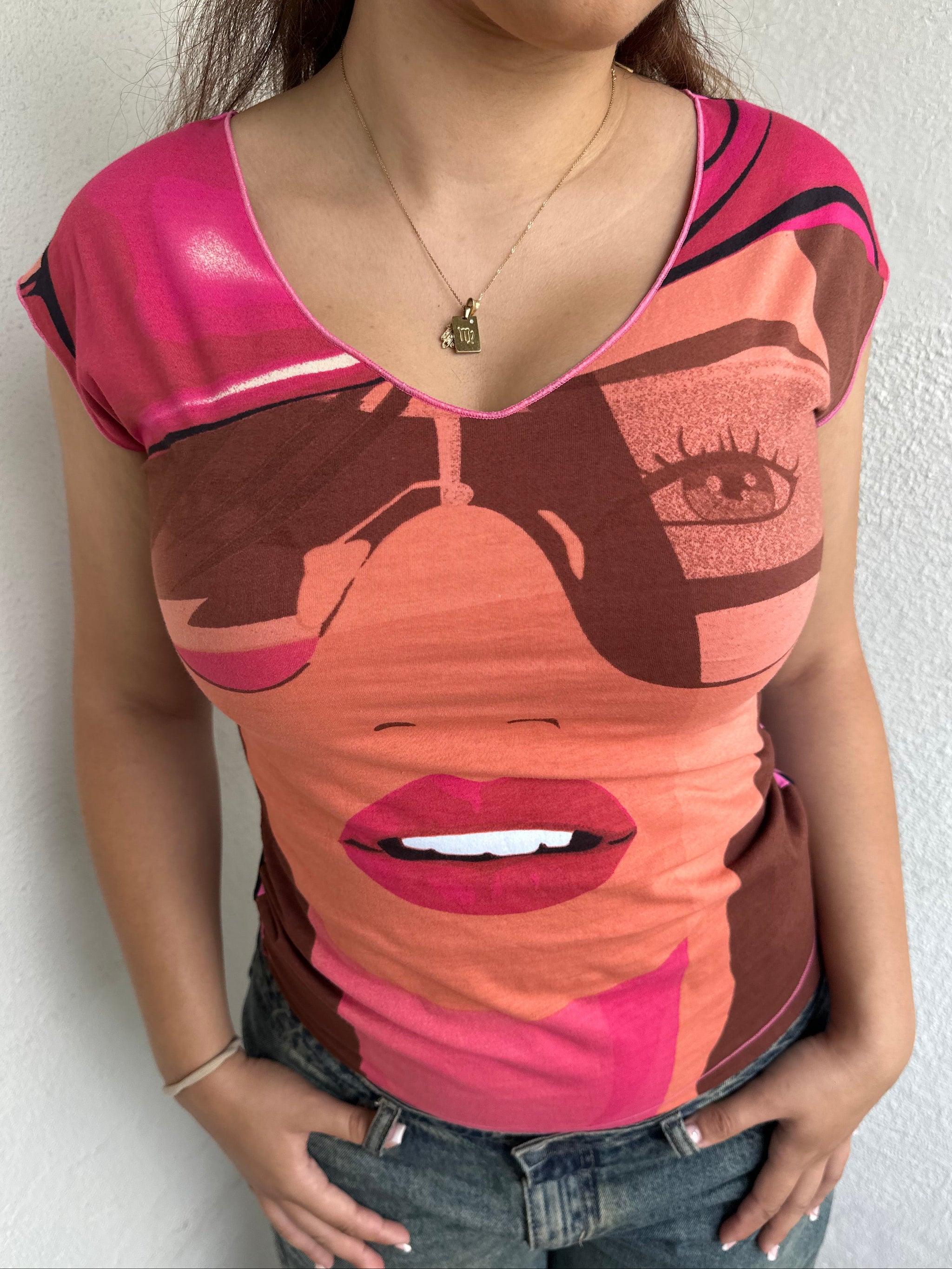 Woman Dressed in Y2K 00s Hot pink graphic t-shirt featuring an illustrated face graphic
