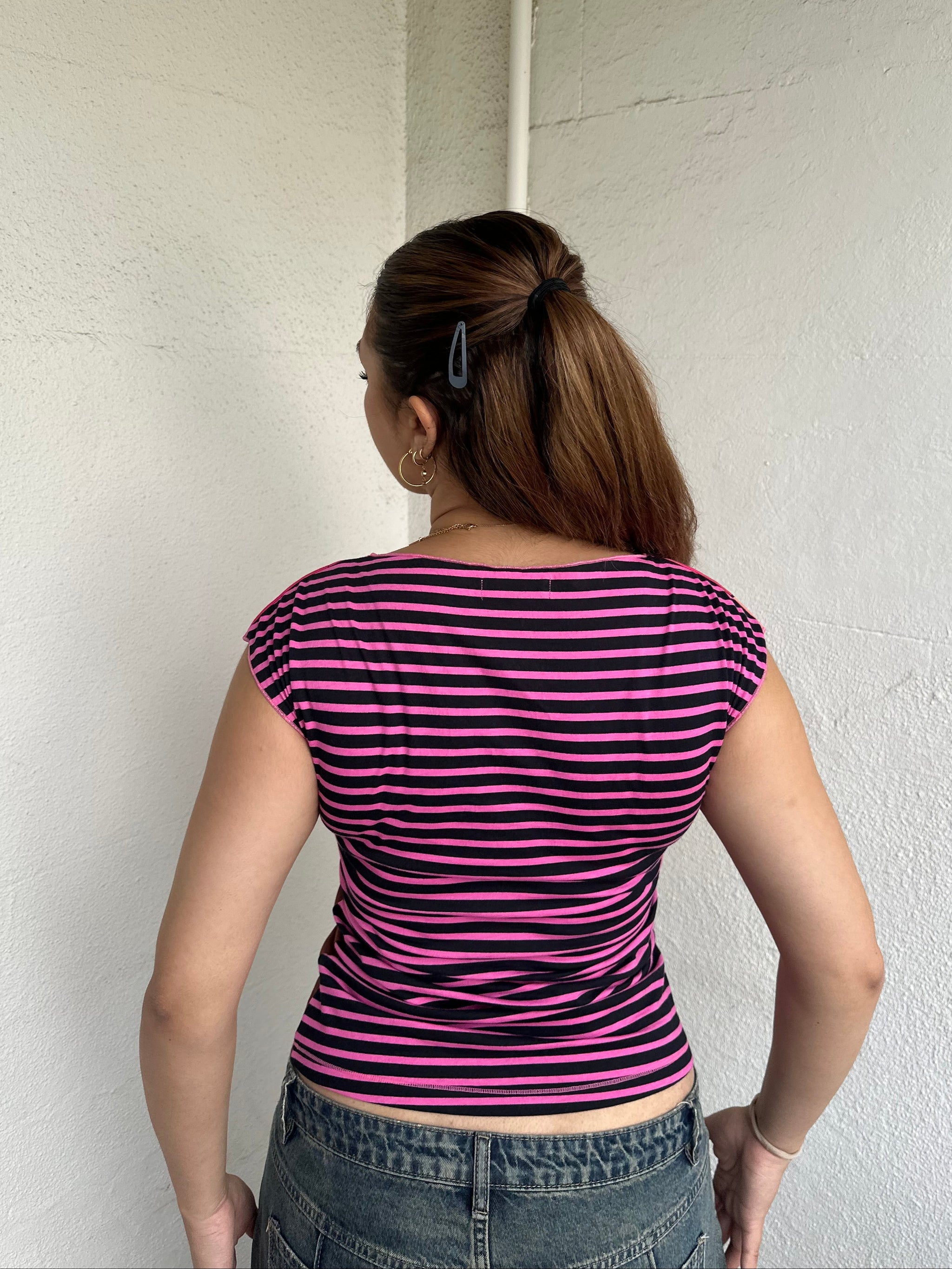 Woman Dressed in Y2K 00s Hot pink graphic t-shirt featuring an illustrated face graphic