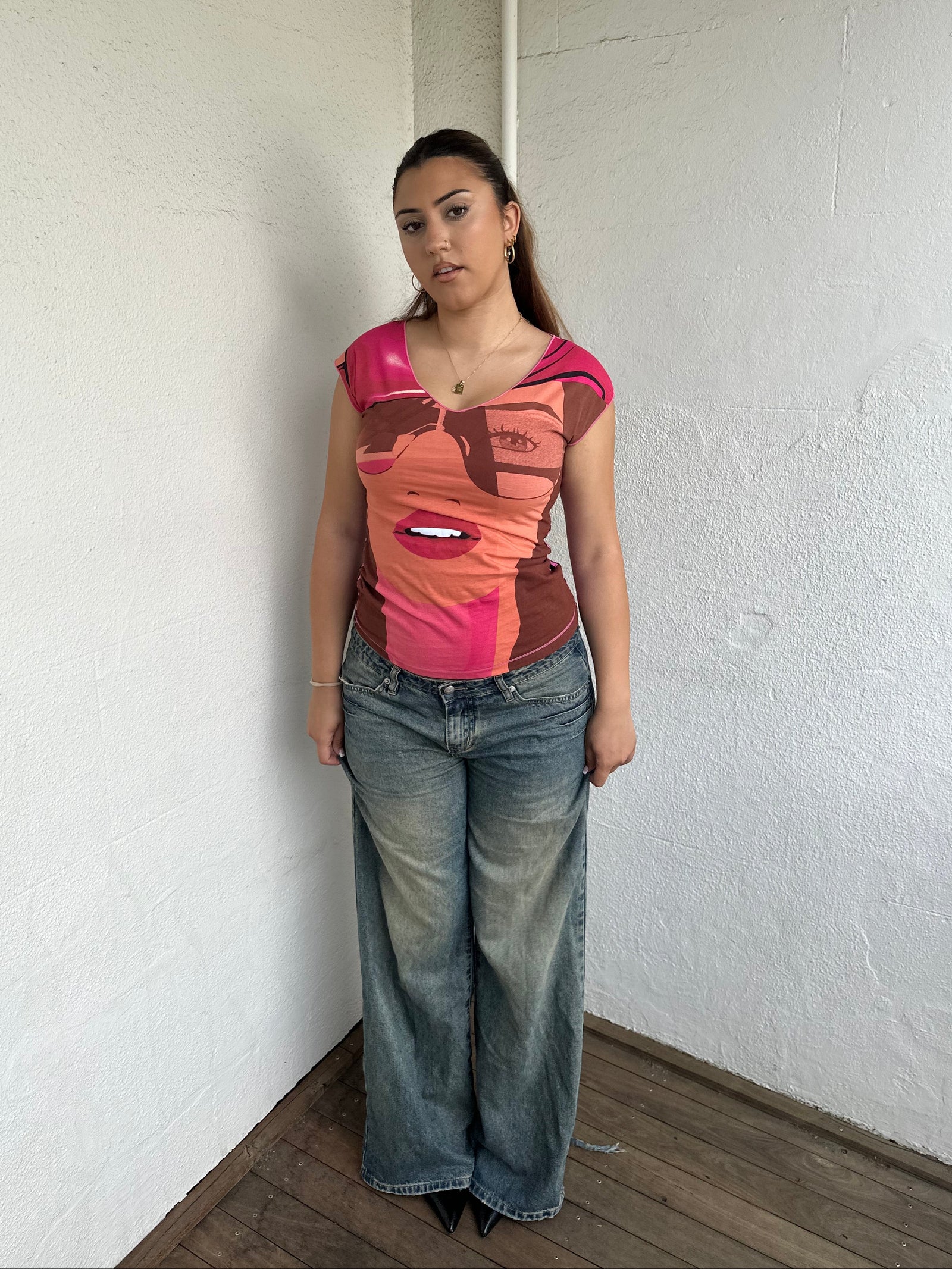 Woman Dressed in Y2K 00s Hot pink graphic t-shirt featuring an illustrated face graphic