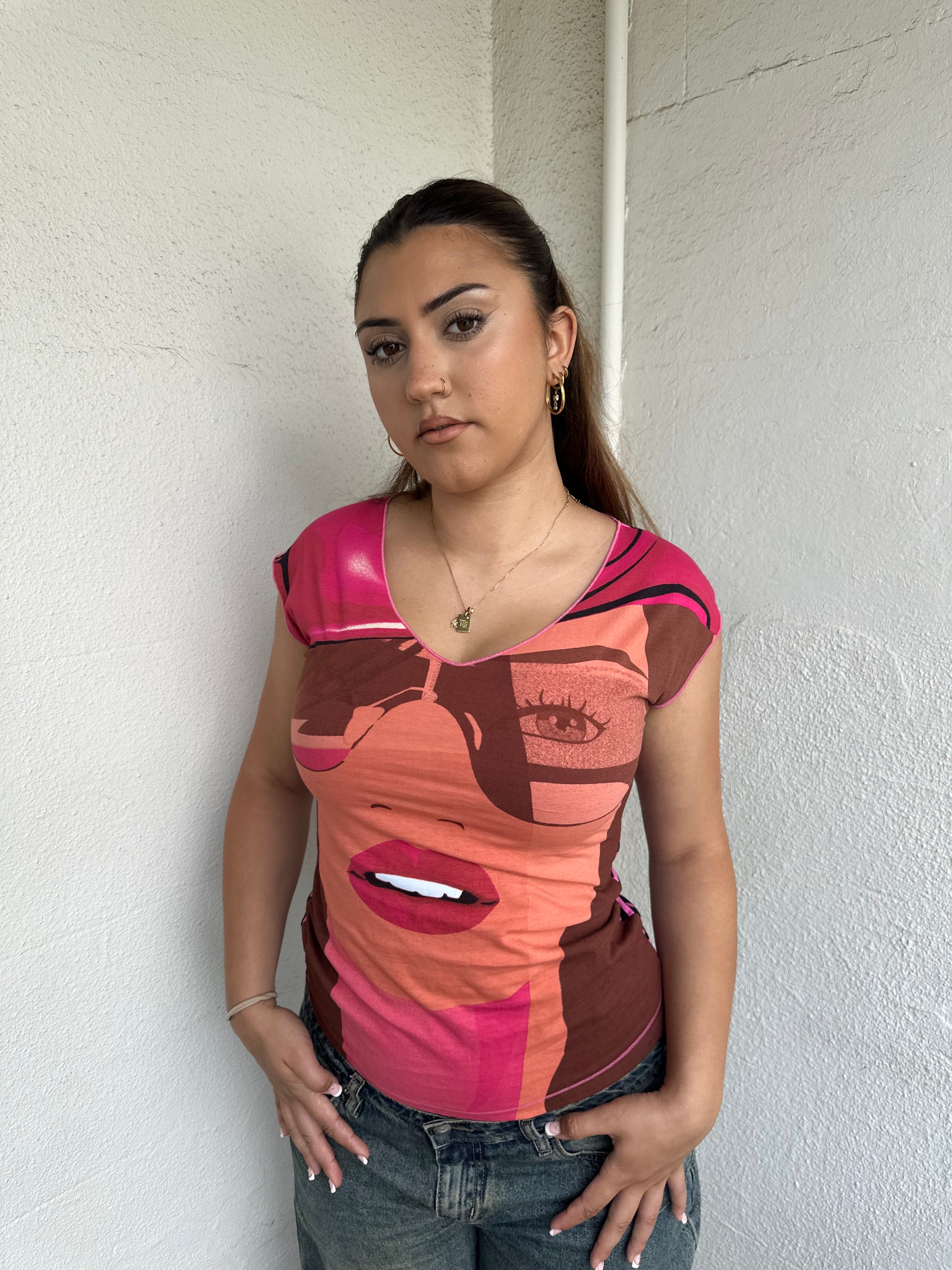 Woman Dressed in Y2K 00s Hot pink graphic t-shirt featuring an illustrated face graphic