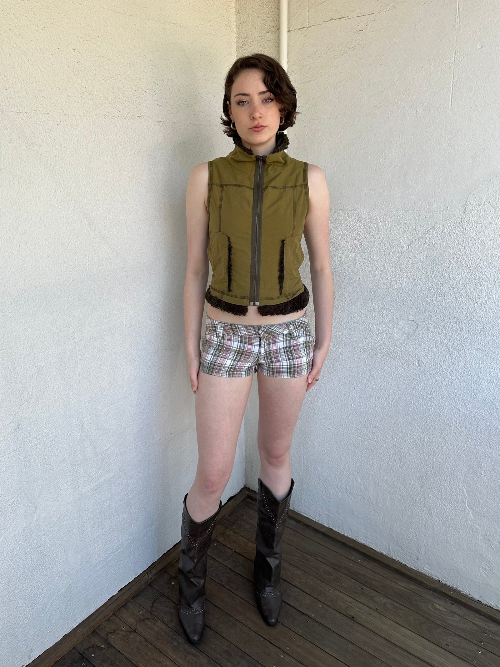 Woman Dressed in Y2K Khaki faux fur trimmed vest featuring plush faux fur trim around the high-neck collar and hem. 