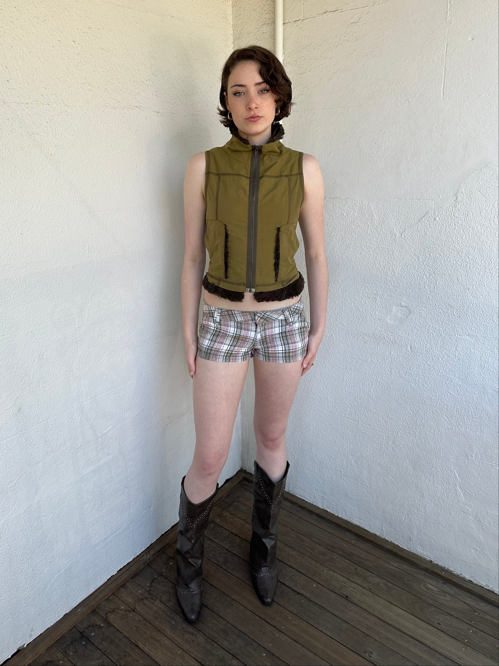Woman Dressed in Y2K Khaki and red tartan shorts featuring a tight booty short silhouette with a low-waist fit. 