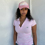 Woman Dressed in Y2K 00s Lacoste baby pink stripe polo with a collared neckline and soft fitted silhouette.