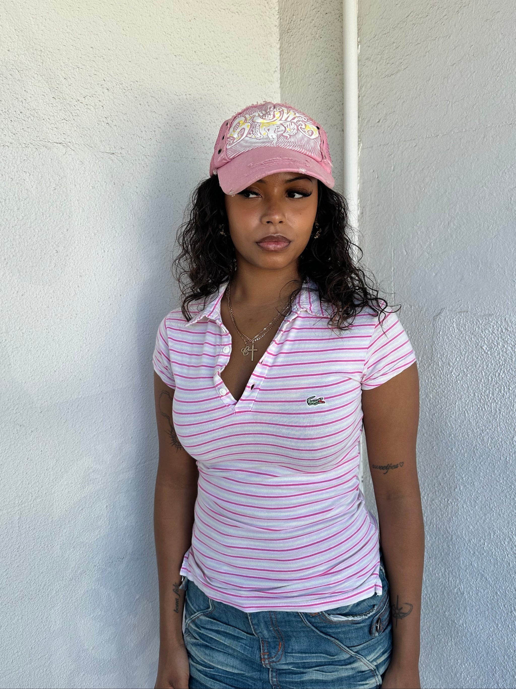 Woman Dressed in Y2K 00s Lacoste baby pink stripe polo with a collared neckline and soft fitted silhouette.
