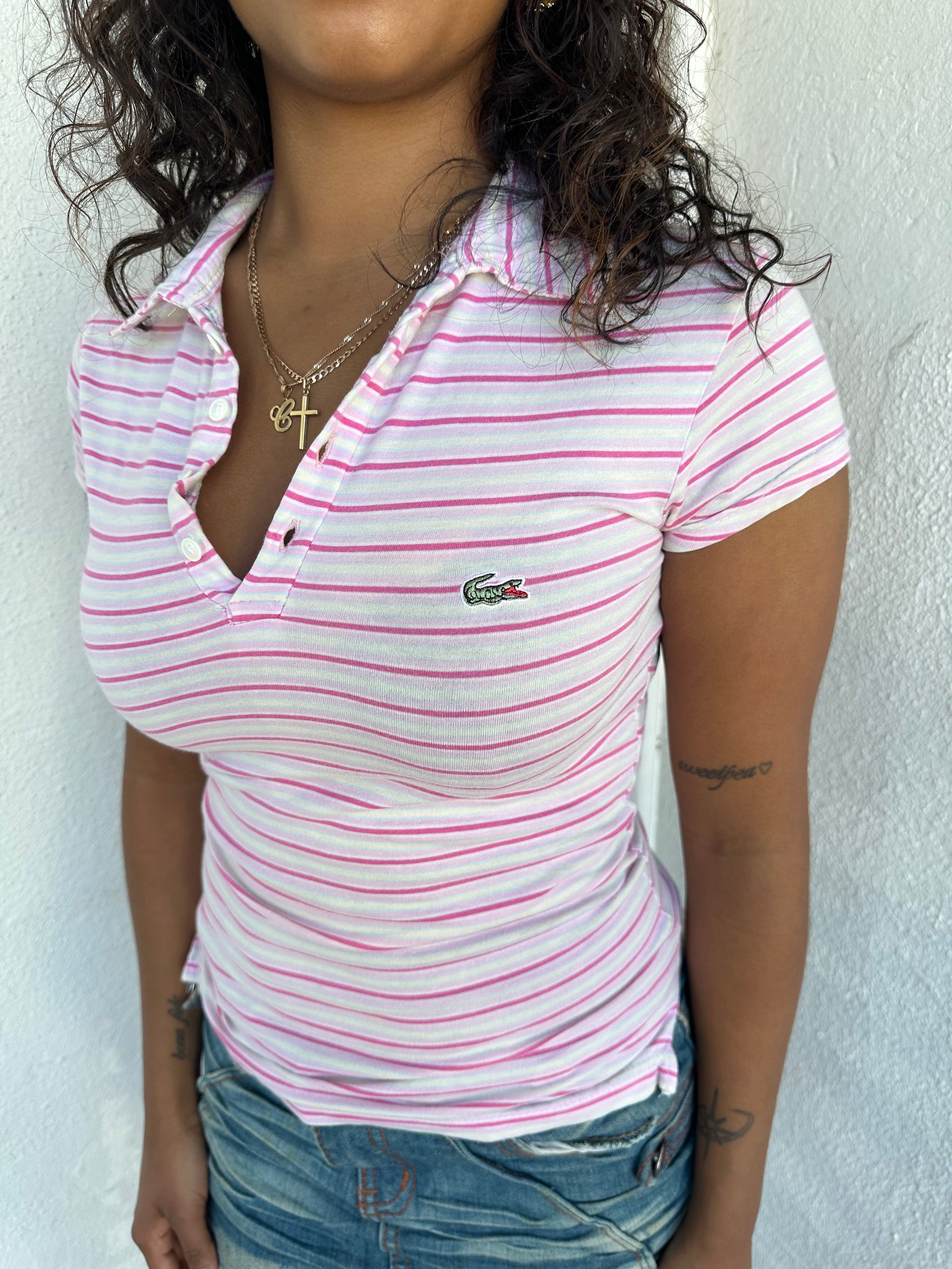 Woman Dressed in Y2K 00s Lacoste baby pink stripe polo with a collared neckline and soft fitted silhouette.