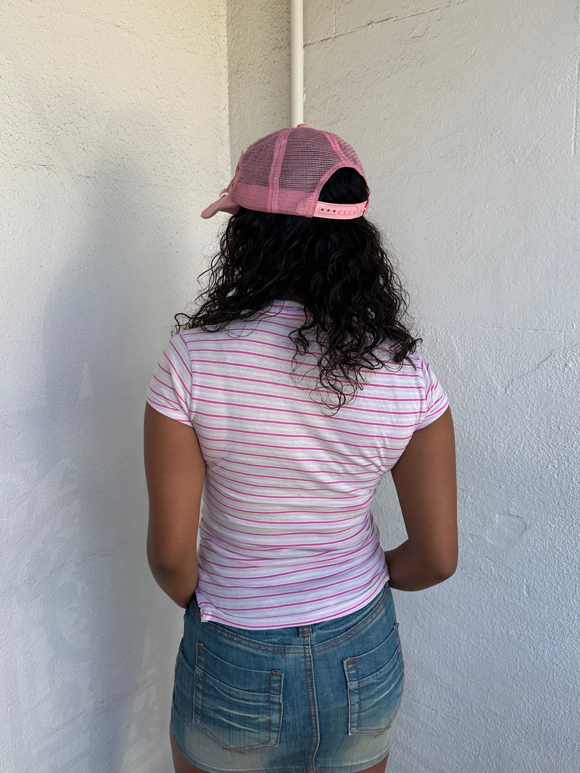 Woman Dressed in Y2K 00s Lacoste baby pink stripe polo with a collared neckline and soft fitted silhouette.