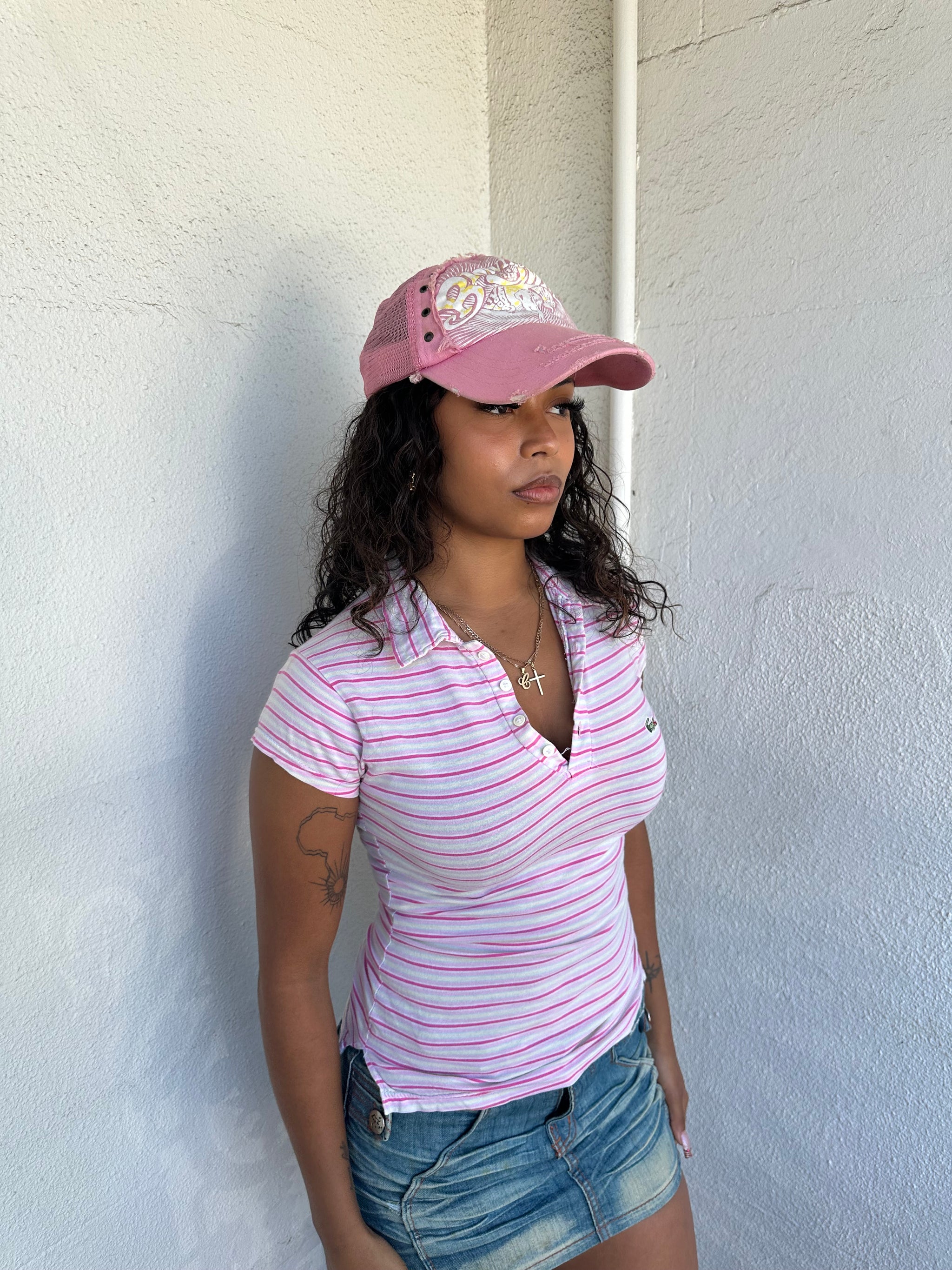 Woman Dressed in Y2K 00s Lacoste baby pink stripe polo with a collared neckline and soft fitted silhouette.