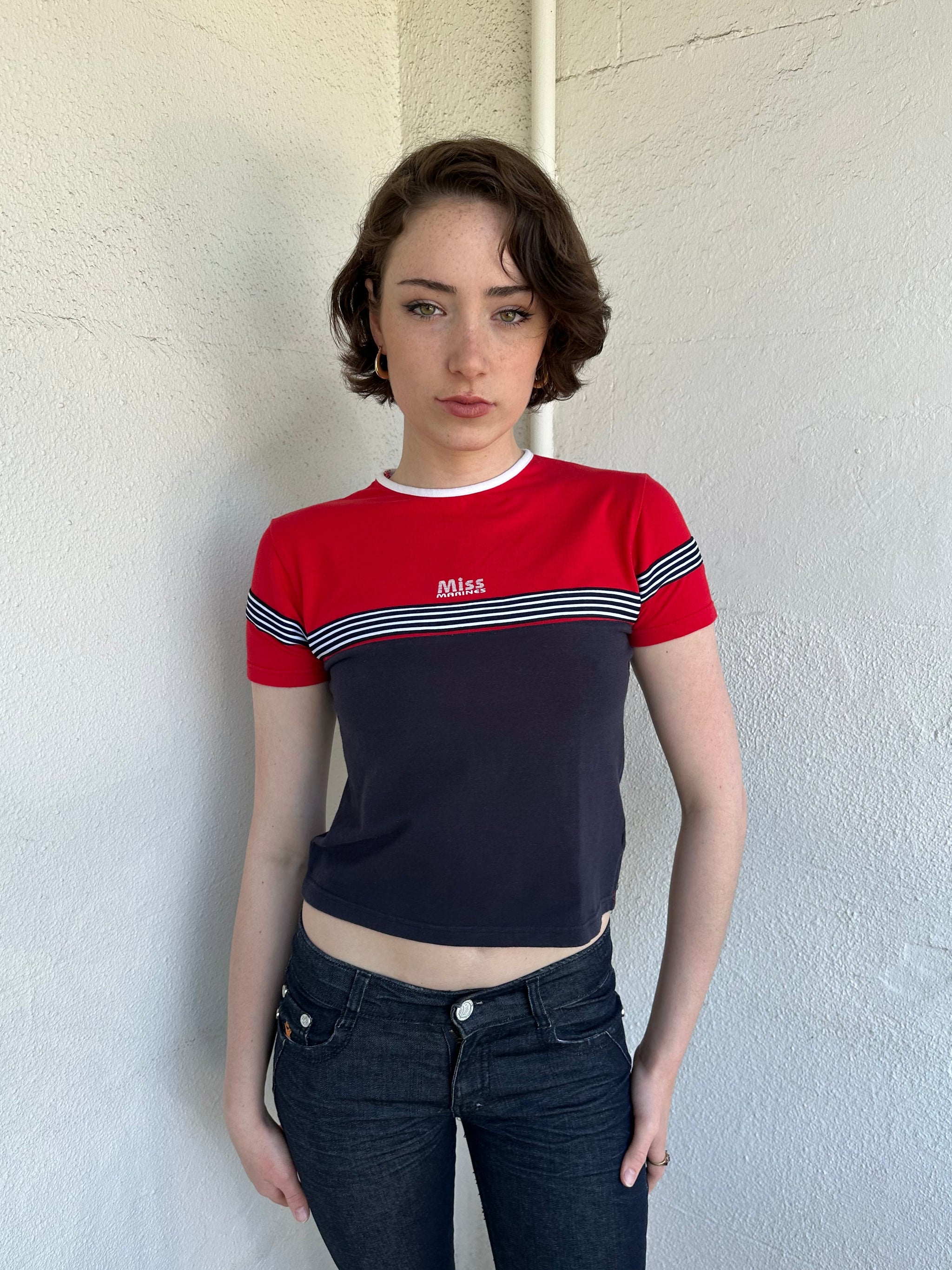 Woman Dressed in Y2K Miss Marines red & navy T-shirt featuring a classic crew neckline with contrasting colour-block panels for a sporty, vintage skater look.