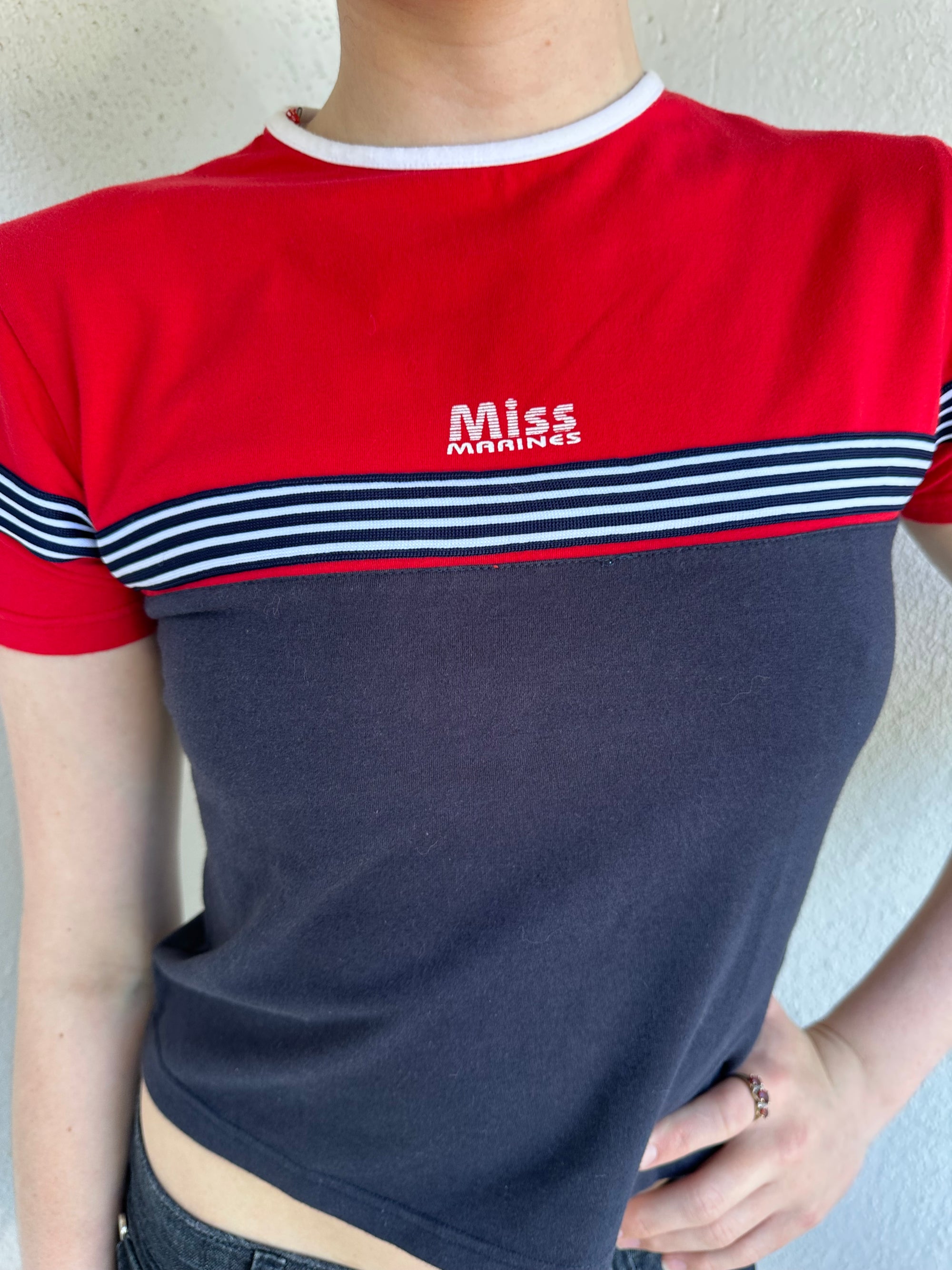 Woman Dressed in Y2K Miss Marines red & navy T-shirt featuring a classic crew neckline with contrasting colour-block panels for a sporty, vintage skater look.