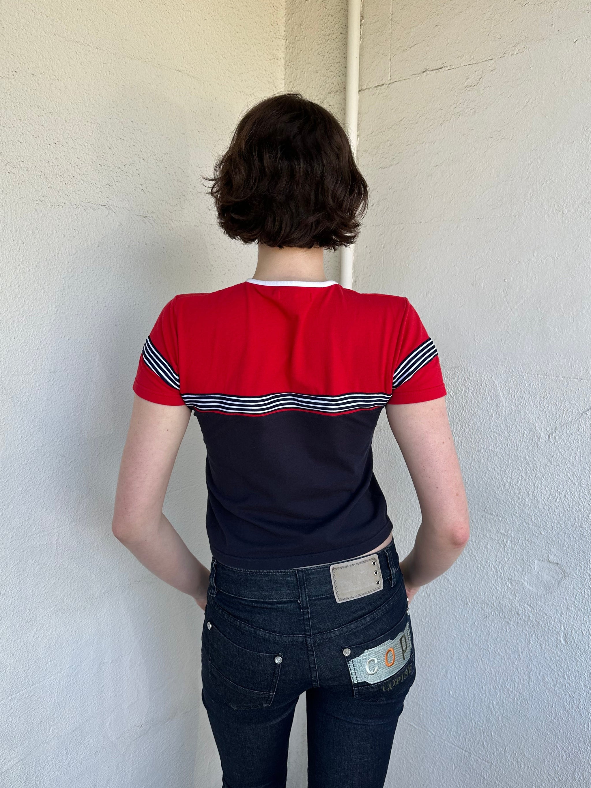 Woman Dressed in Y2K Miss Marines red & navy T-shirt featuring a classic crew neckline with contrasting colour-block panels for a sporty, vintage skater look.