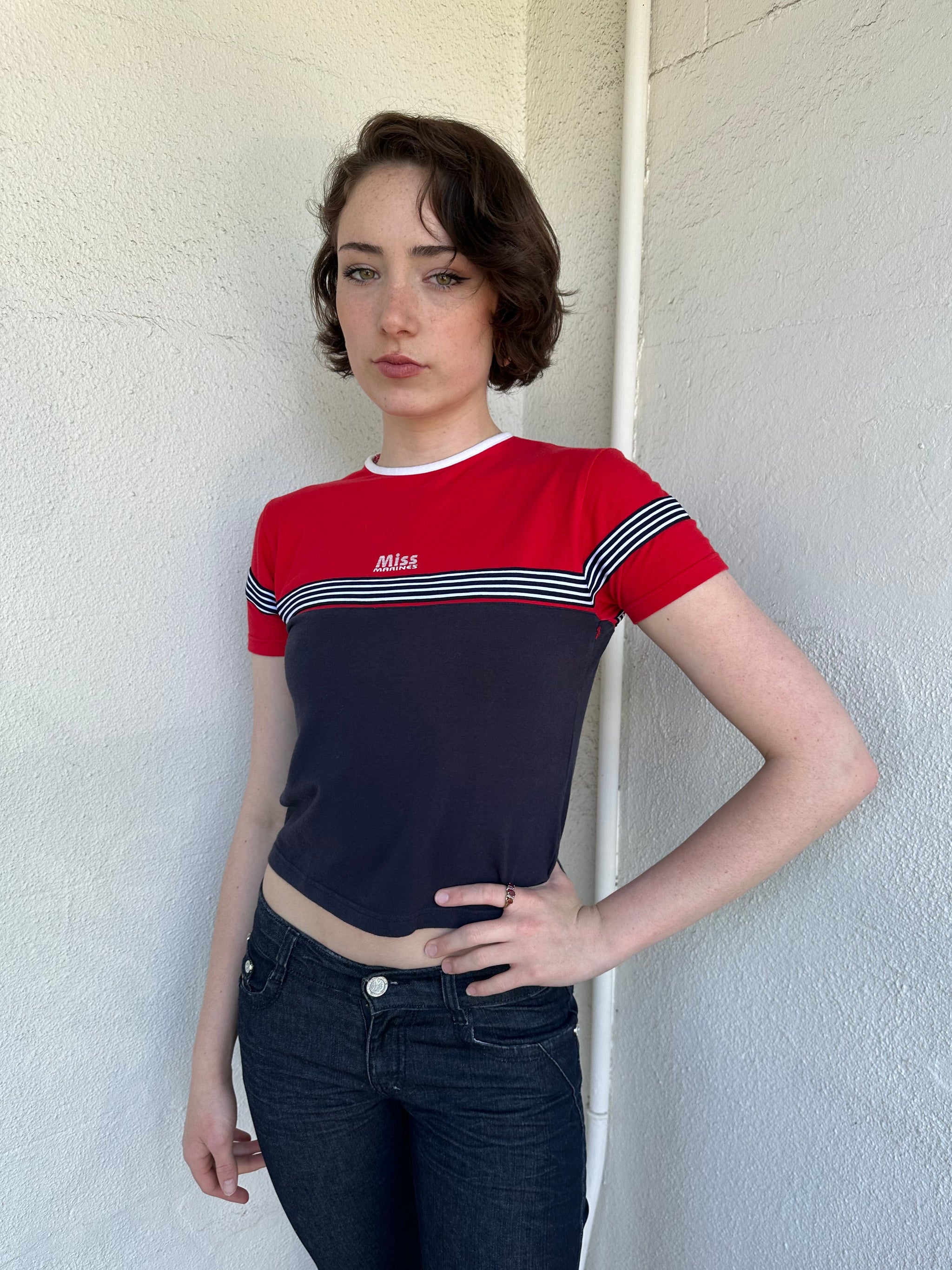 Woman Dressed in Y2K Miss Marines red & navy T-shirt featuring a classic crew neckline with contrasting colour-block panels for a sporty, vintage skater look.