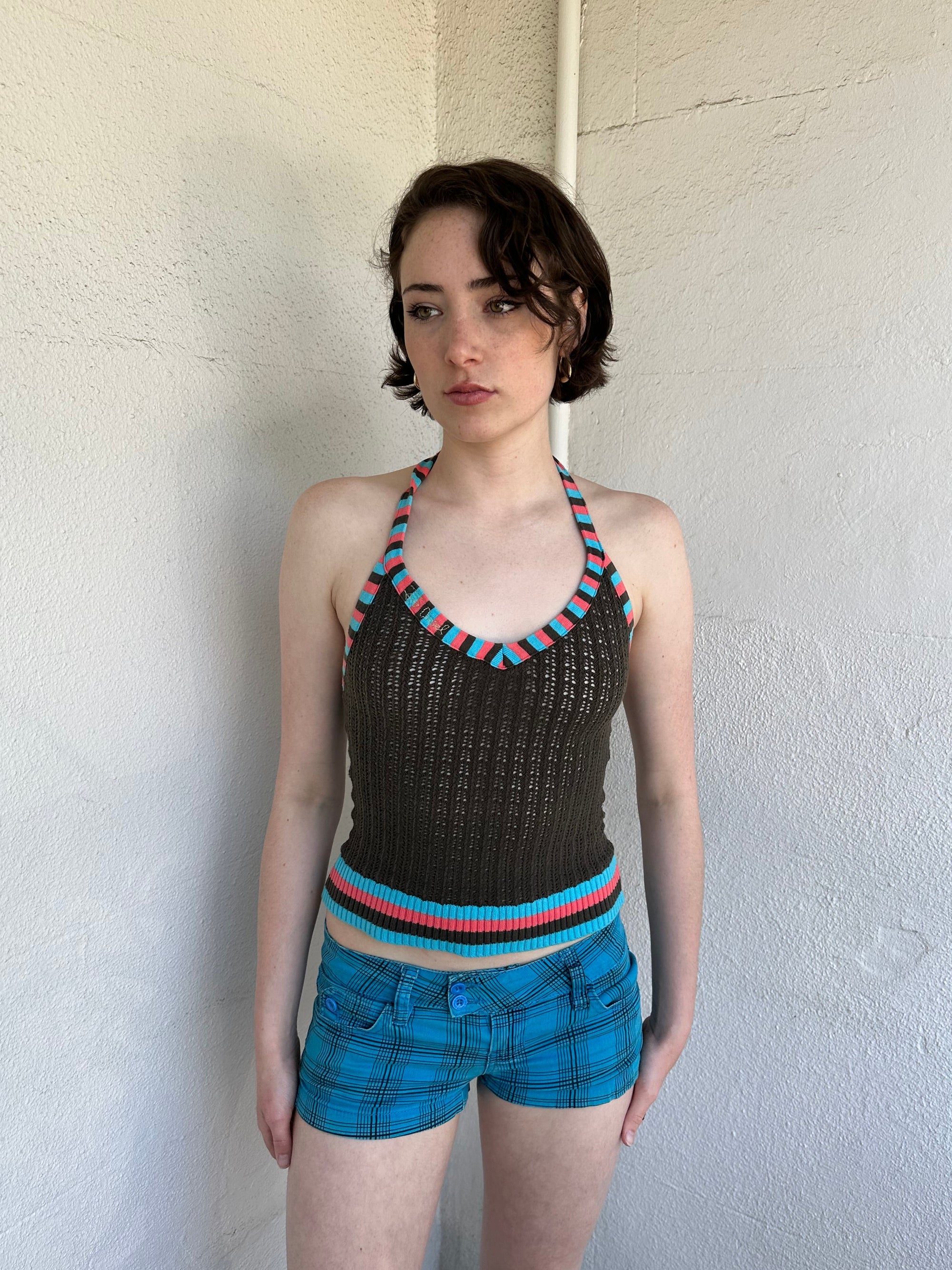 Woman Dressed in Y2K Multicoloured knitted halter top featuring a brown knitted body with contrasting blue and orange striped trim along the halter strap and hem.
