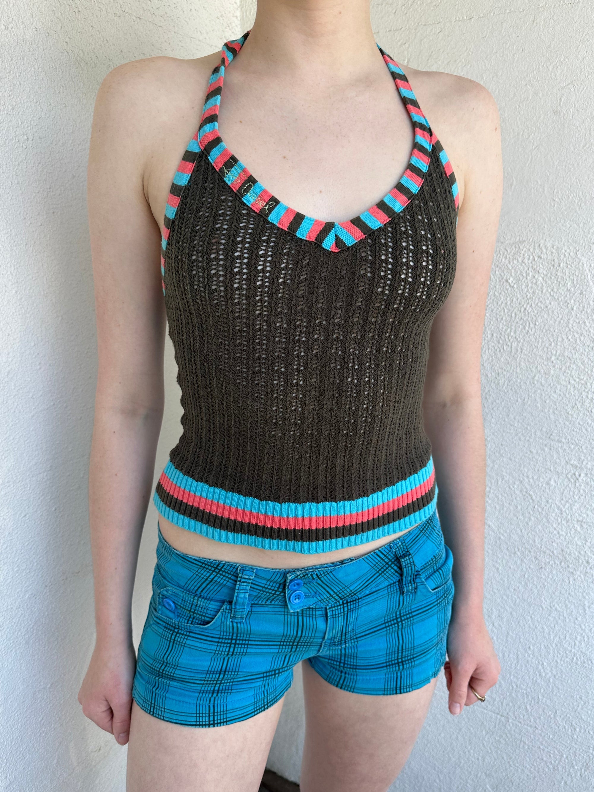 Woman Dressed in Y2K Multicoloured knitted halter top featuring a brown knitted body with contrasting blue and orange striped trim along the halter strap and hem.