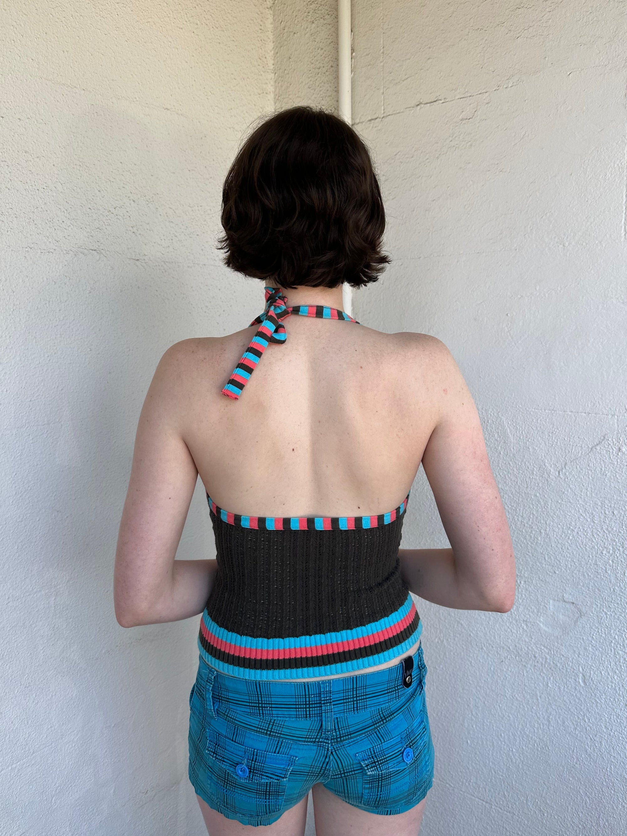 Woman Dressed in Y2K Multicoloured knitted halter top featuring a brown knitted body with contrasting blue and orange striped trim along the halter strap and hem.