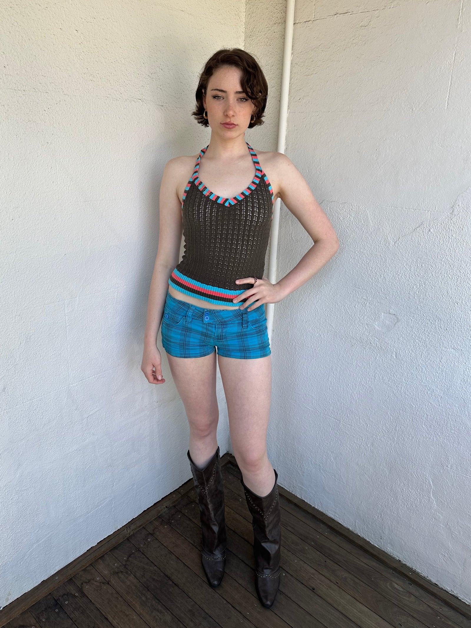 Woman Dressed in Y2K Multicoloured knitted halter top featuring a brown knitted body with contrasting blue and orange striped trim along the halter strap and hem.