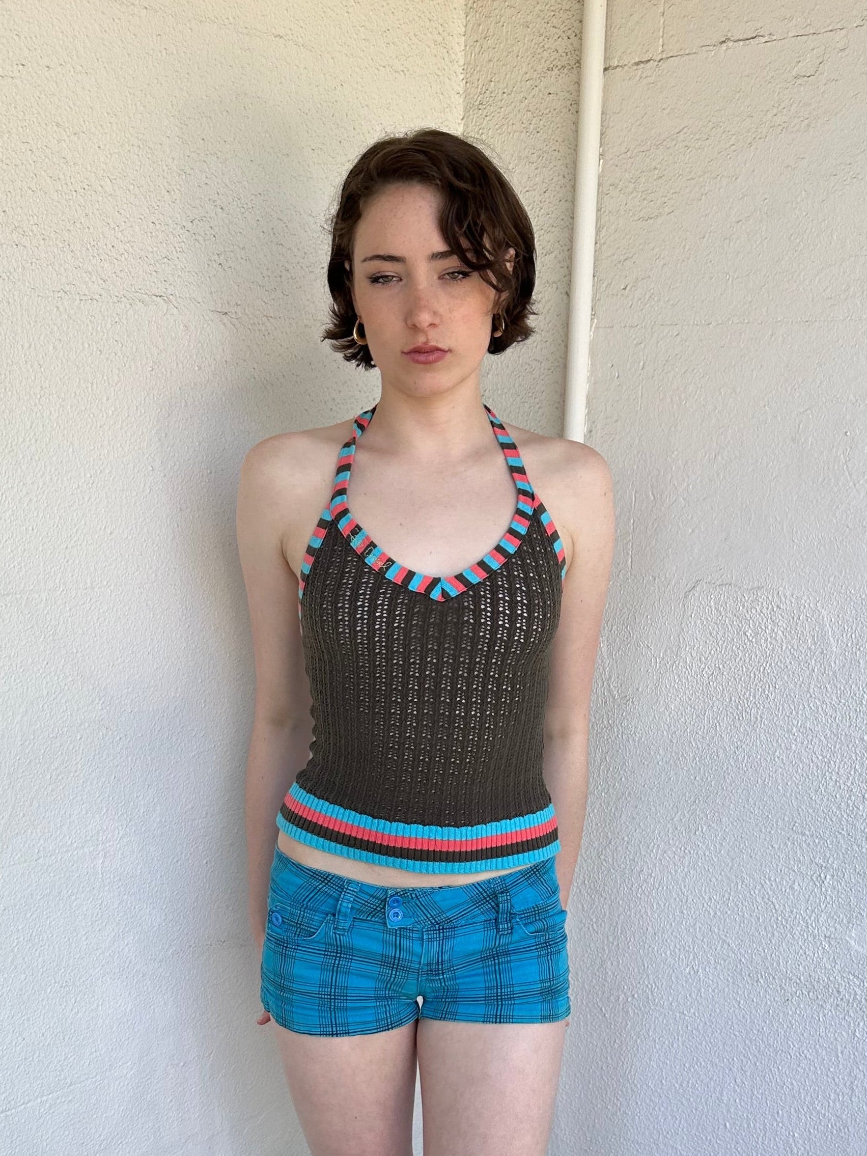 Woman Dressed in Y2K Multicoloured knitted halter top featuring a brown knitted body with contrasting blue and orange striped trim along the halter strap and hem.