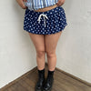 Woman Dressed in Y2K 00s Navy polkadot mini skort featuring a classic navy base with white polkadot detailing. 