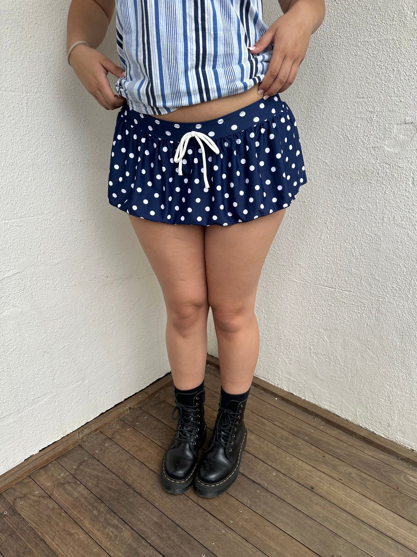 Woman Dressed in Y2K 00s Navy polkadot mini skort featuring a classic navy base with white polkadot detailing. 