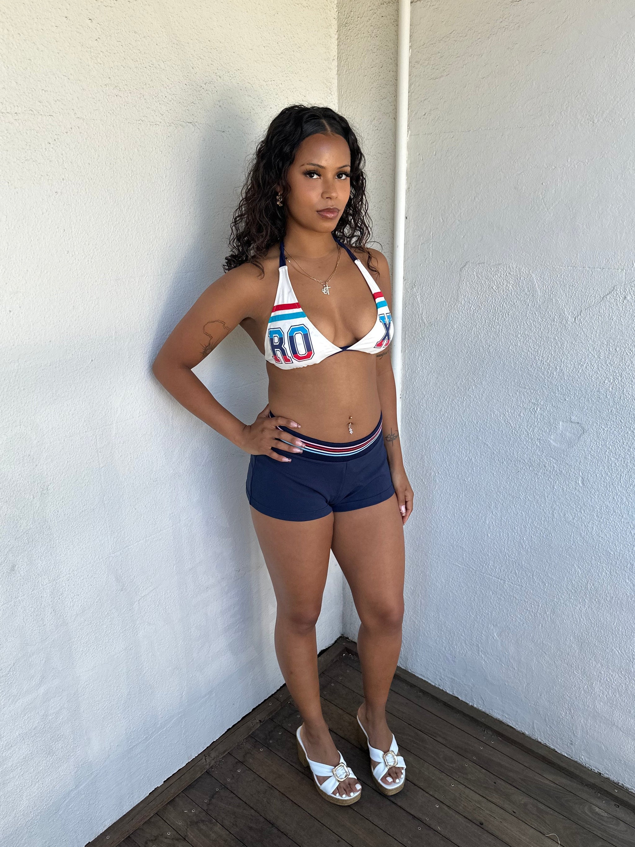 Woman Dressed in Y2K 00s Navy printed booty shorts featuring a navy base with “Roco Nails” printed across the bum. 