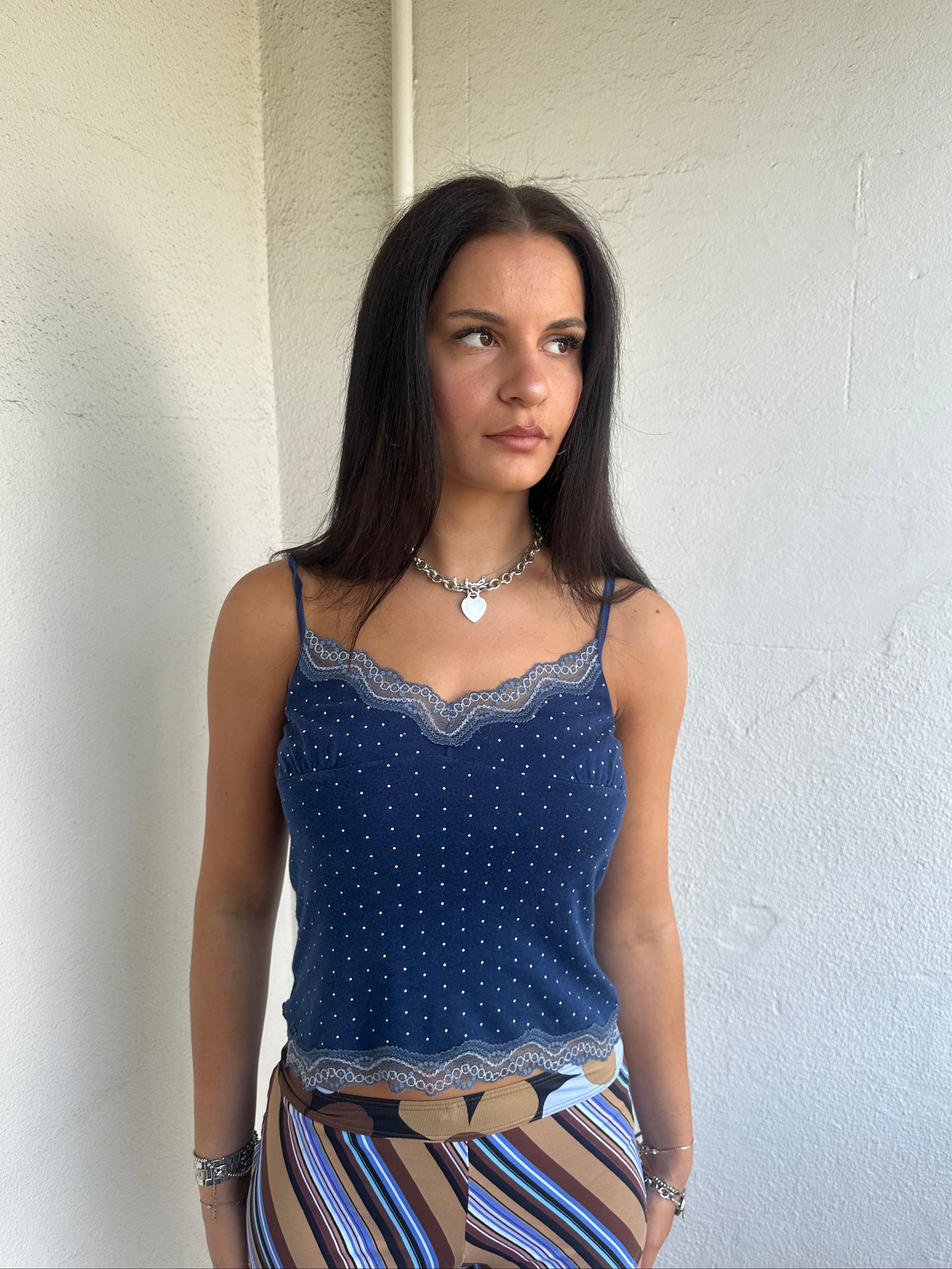 Woman Dressed in Y2K 00s Navy and white polkadot Y2K cami featuring a classic navy base with white polkadot detailing and lace trim along the bust.