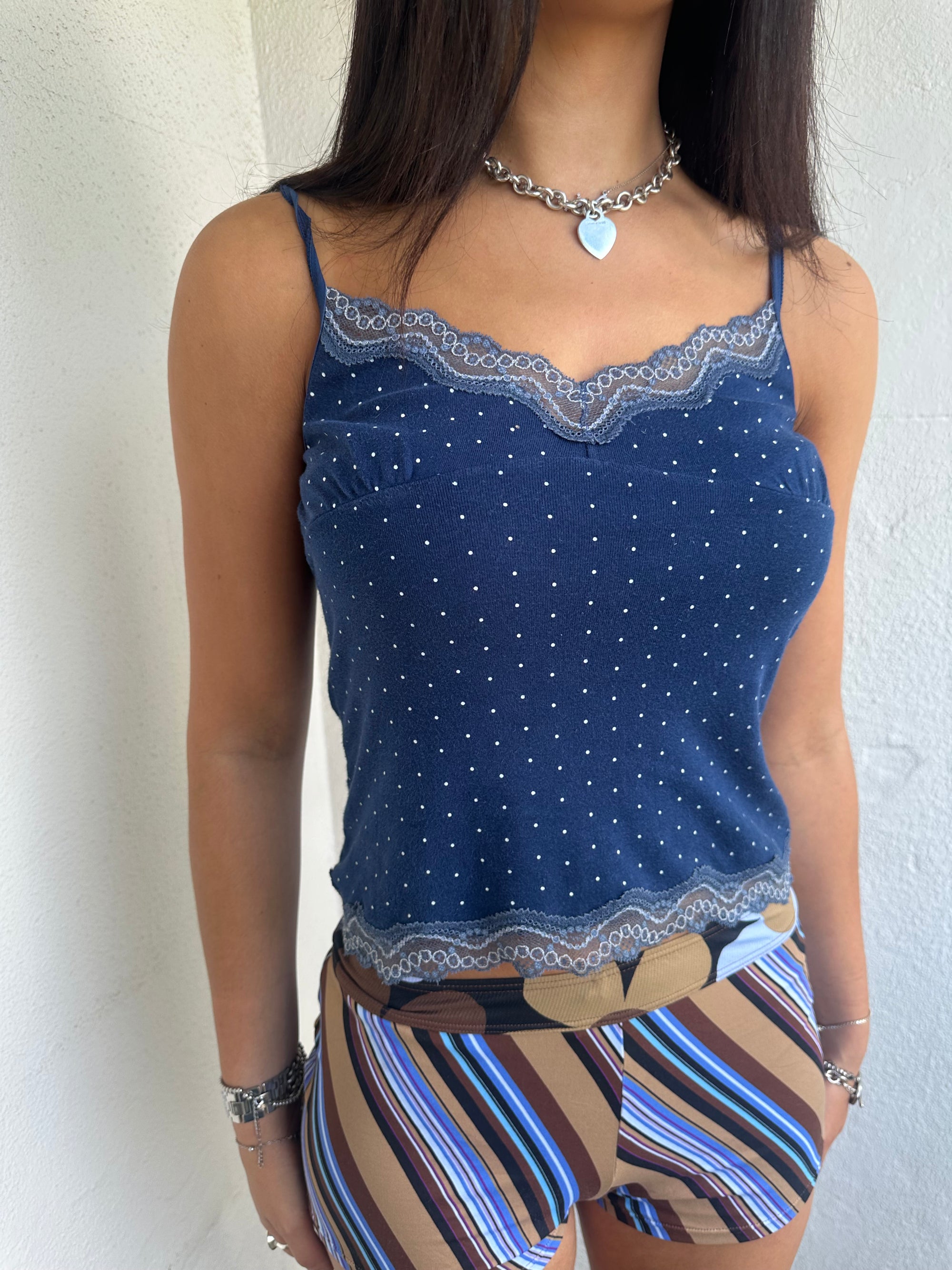 Woman Dressed in Y2K 00s Navy and white polkadot Y2K cami featuring a classic navy base with white polkadot detailing and lace trim along the bust.