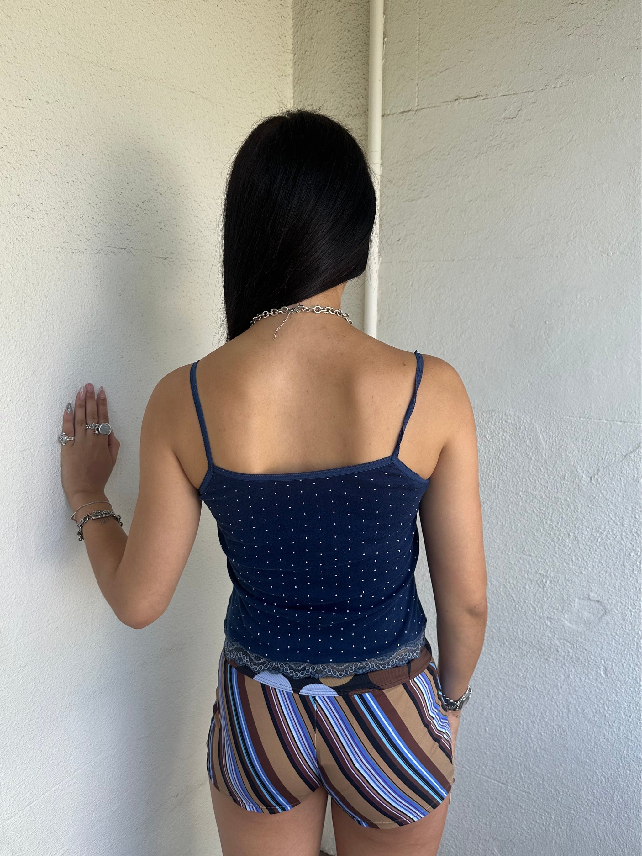 Woman Dressed in Y2K 00s Navy and white polkadot Y2K cami featuring a classic navy base with white polkadot detailing and lace trim along the bust.