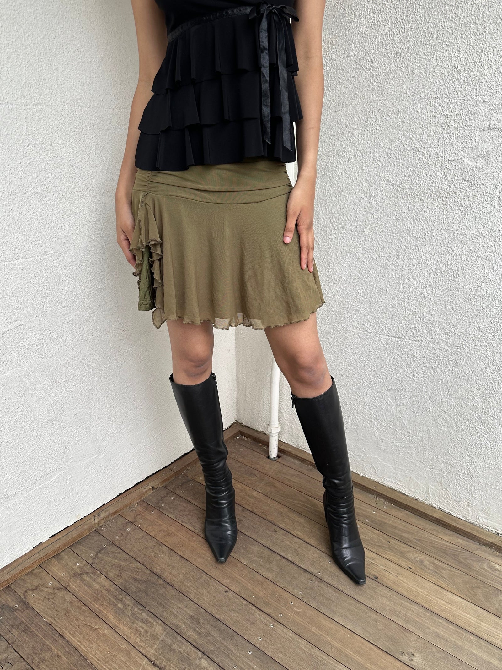 Woman Dressed in Y2K 00s Olive green mesh layered skirt featuring soft mesh layers with a side slit