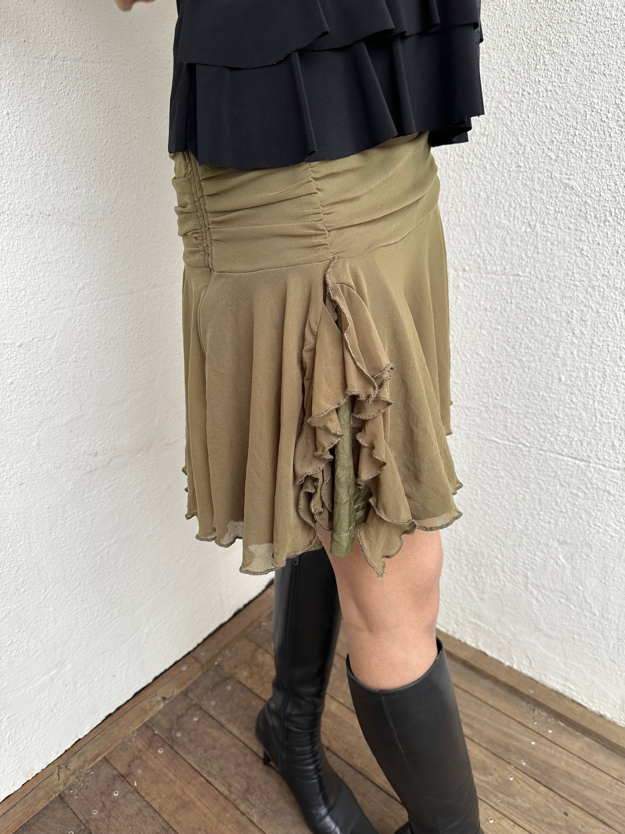 Woman Dressed in Y2K 00s Olive green mesh layered skirt featuring soft mesh layers with a side slit