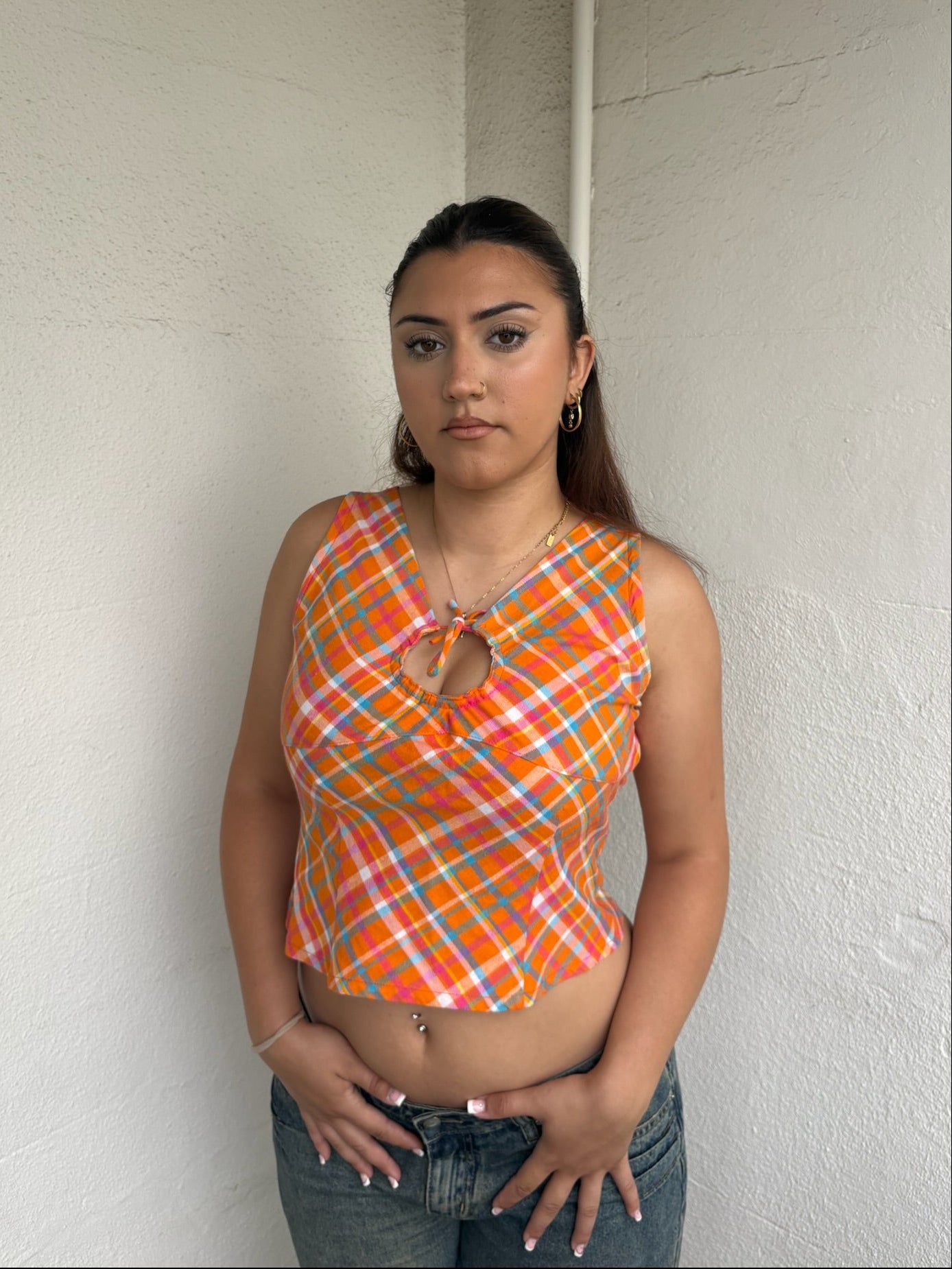 Woman Dressed in Y2K 00s Orange checkered Y2K tank top featuring a bold multi coloured check pattern 