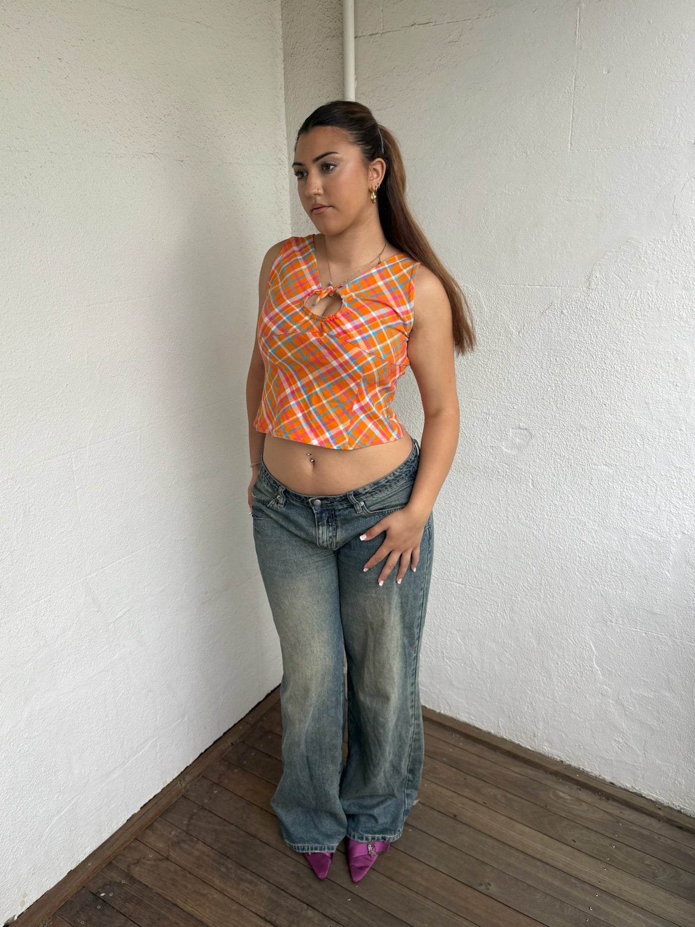 Woman Dressed in Y2K 00s Orange checkered Y2K tank top featuring a bold multi coloured check pattern 