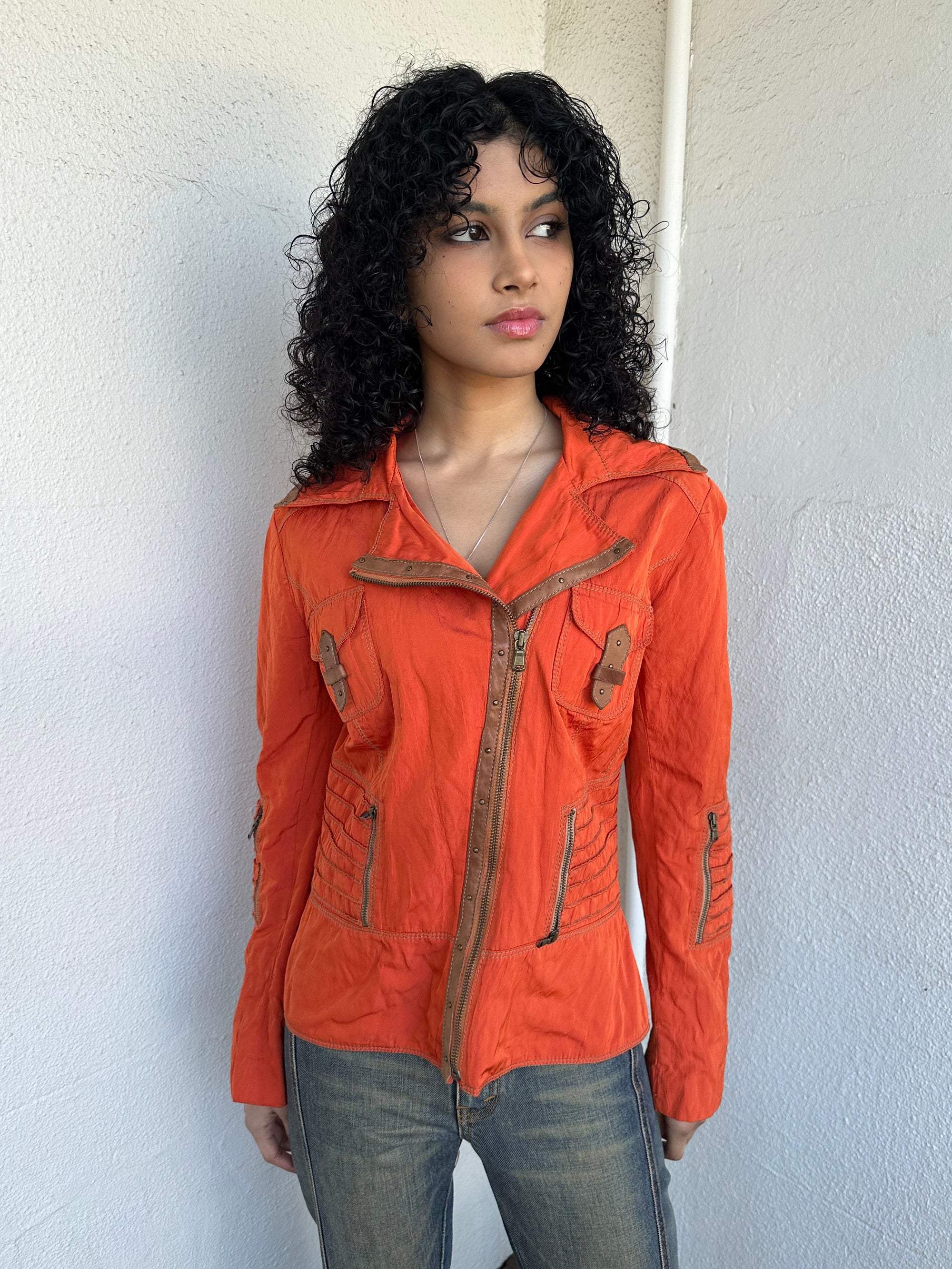 Woman wearing a Y2K 00s Incredible orange two tone jacket channels a modern biker aesthetic