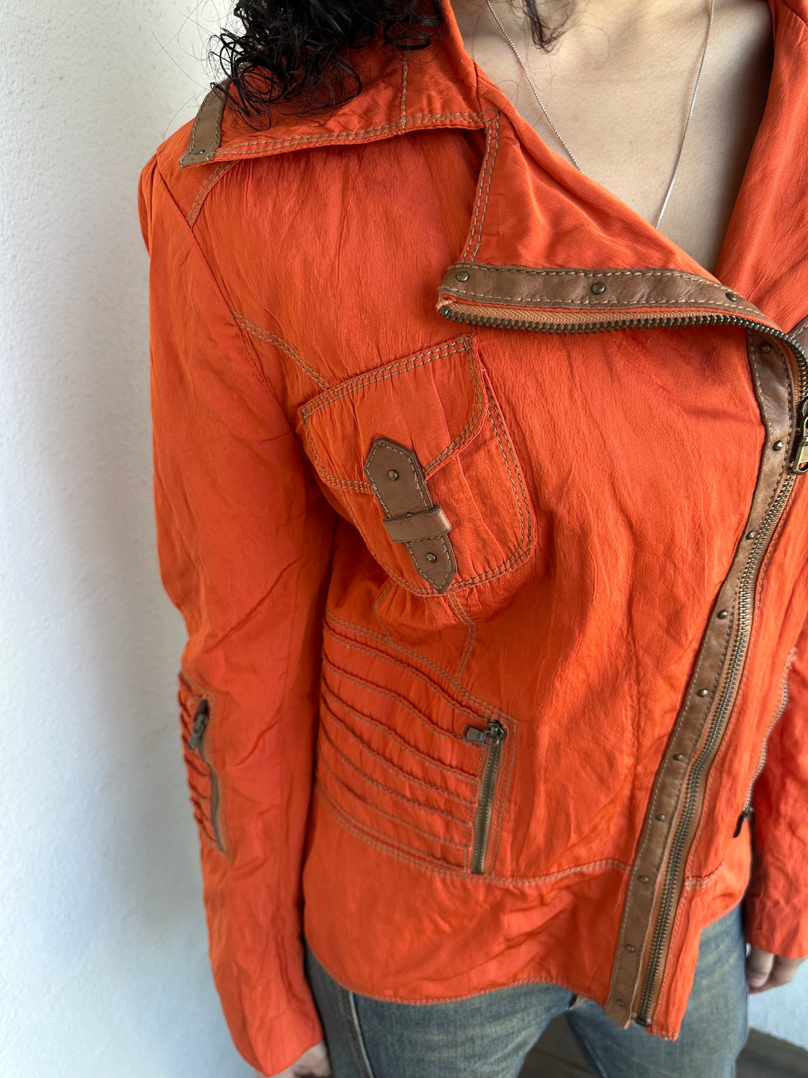 Woman wearing a Y2K 00s Incredible orange two tone jacket channels a modern biker aesthetic