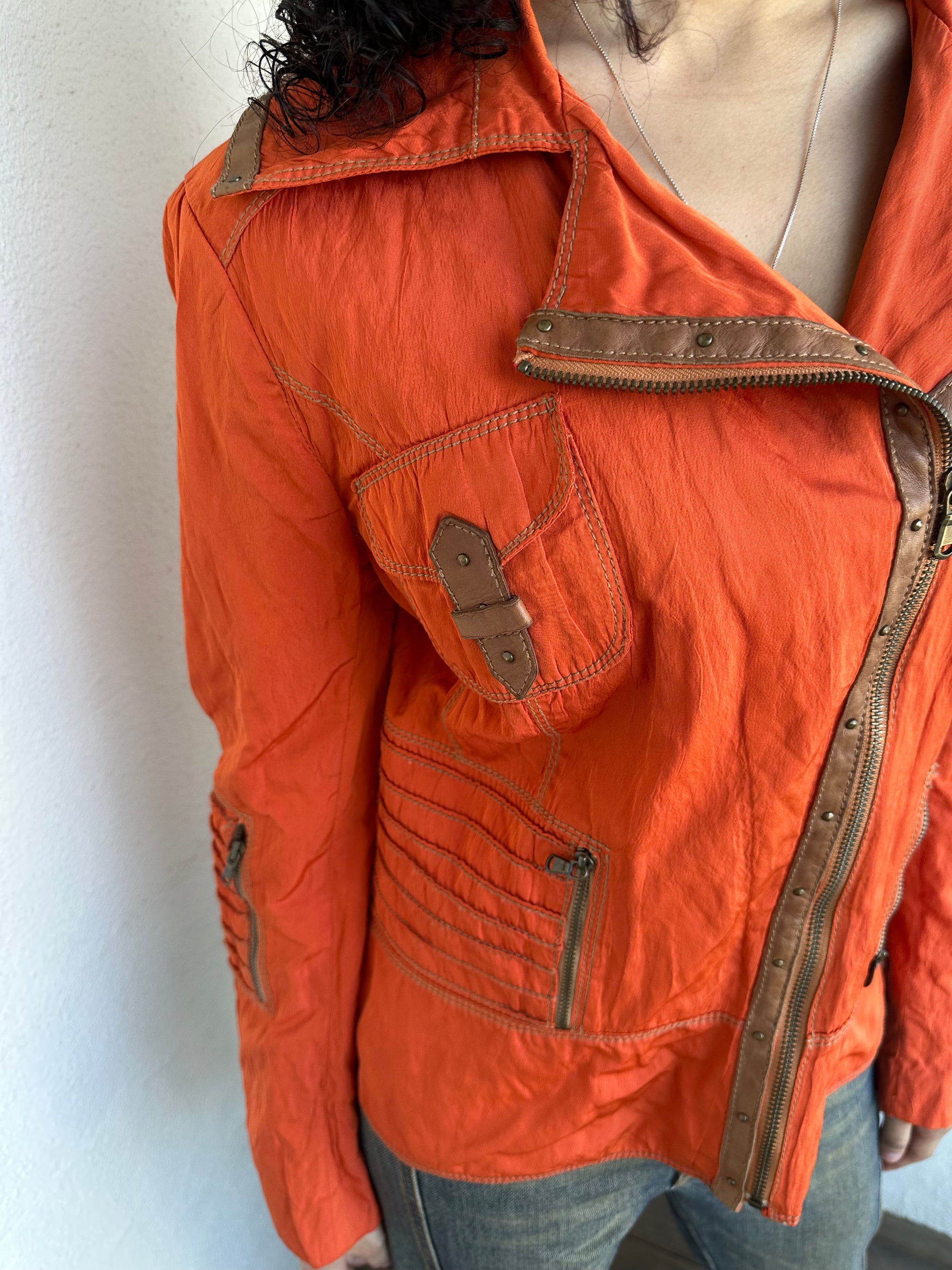 Woman wearing a Y2K 00s Incredible orange two tone jacket channels a modern biker aesthetic