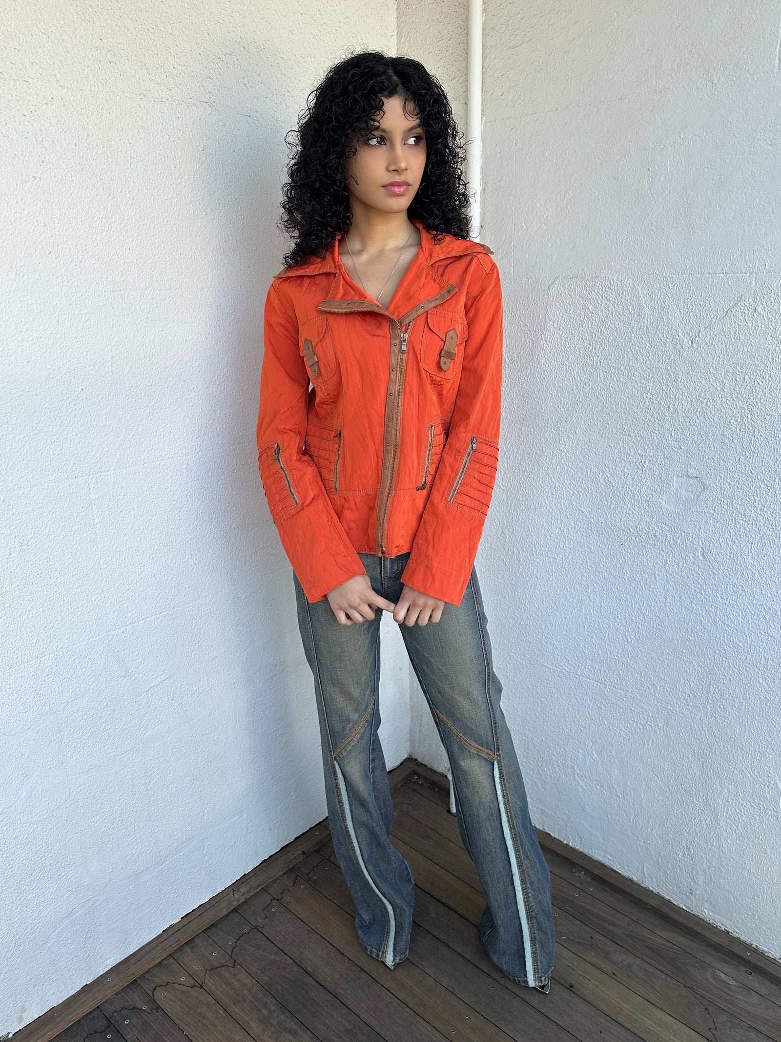 Woman wearing a Y2K 00s Incredible orange two tone jacket channels a modern biker aesthetic