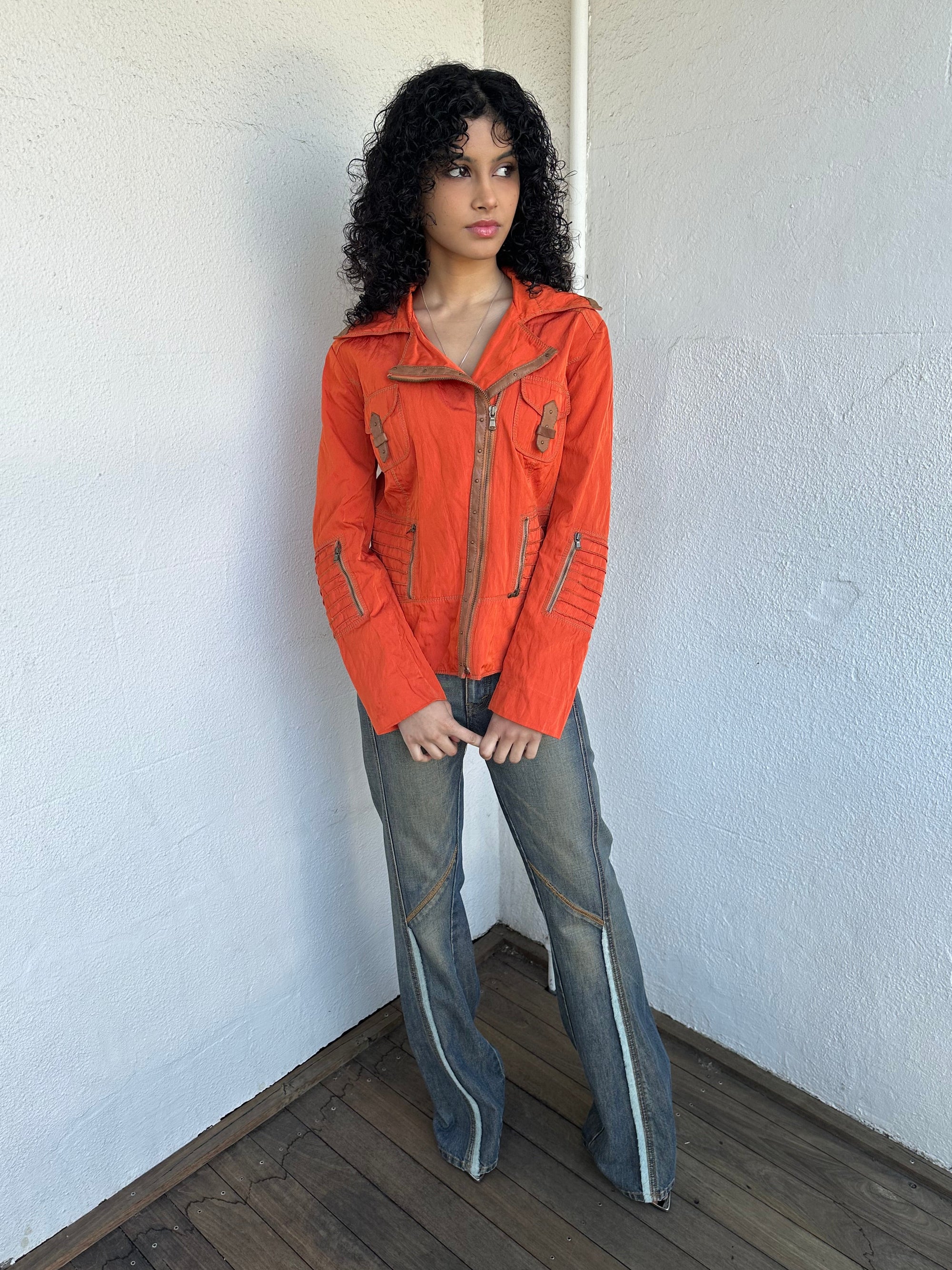 Woman wearing a Y2K 00s Incredible orange two tone jacket channels a modern biker aesthetic