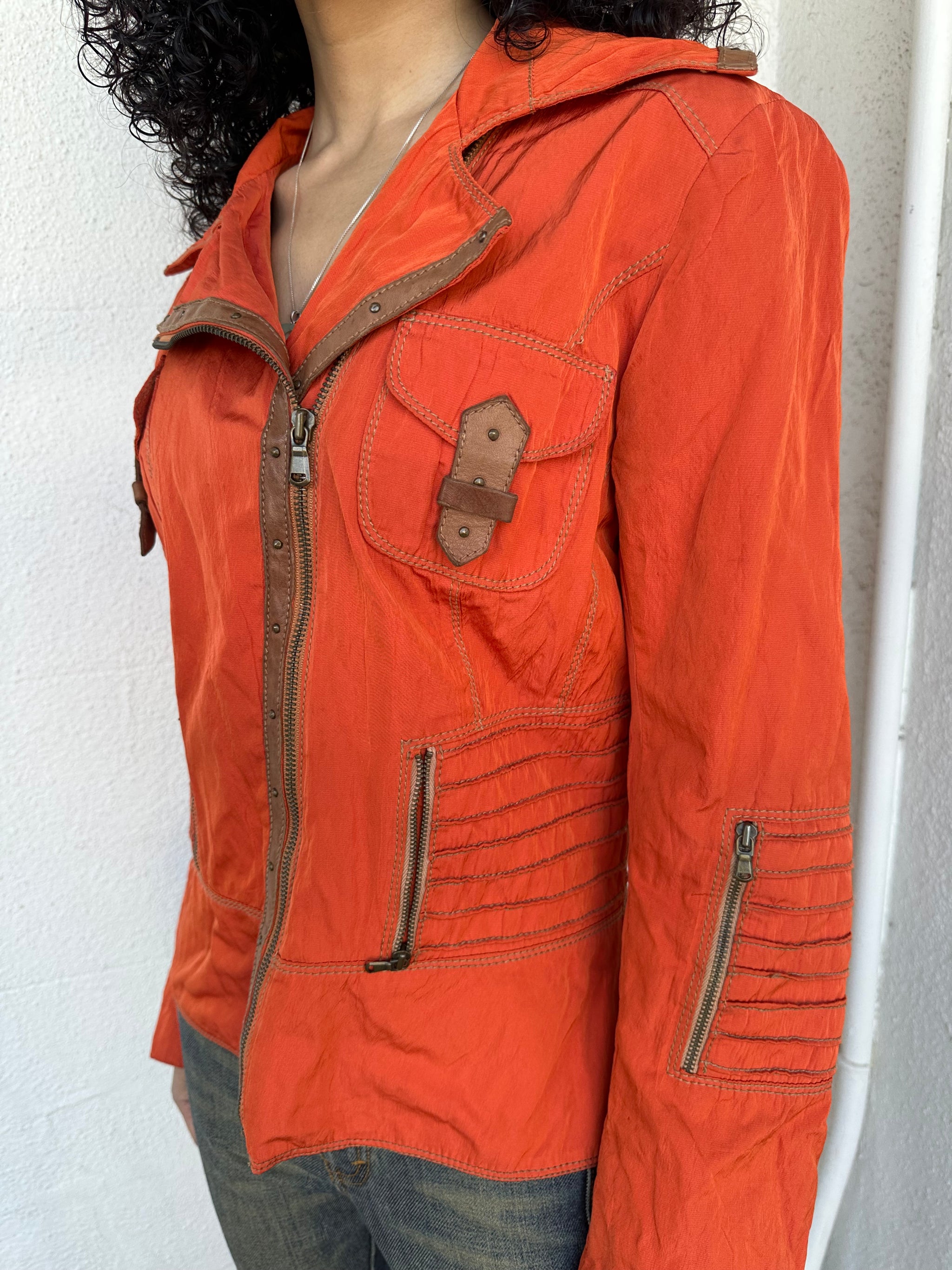 Woman wearing a Y2K 00s Incredible orange two tone jacket channels a modern biker aesthetic