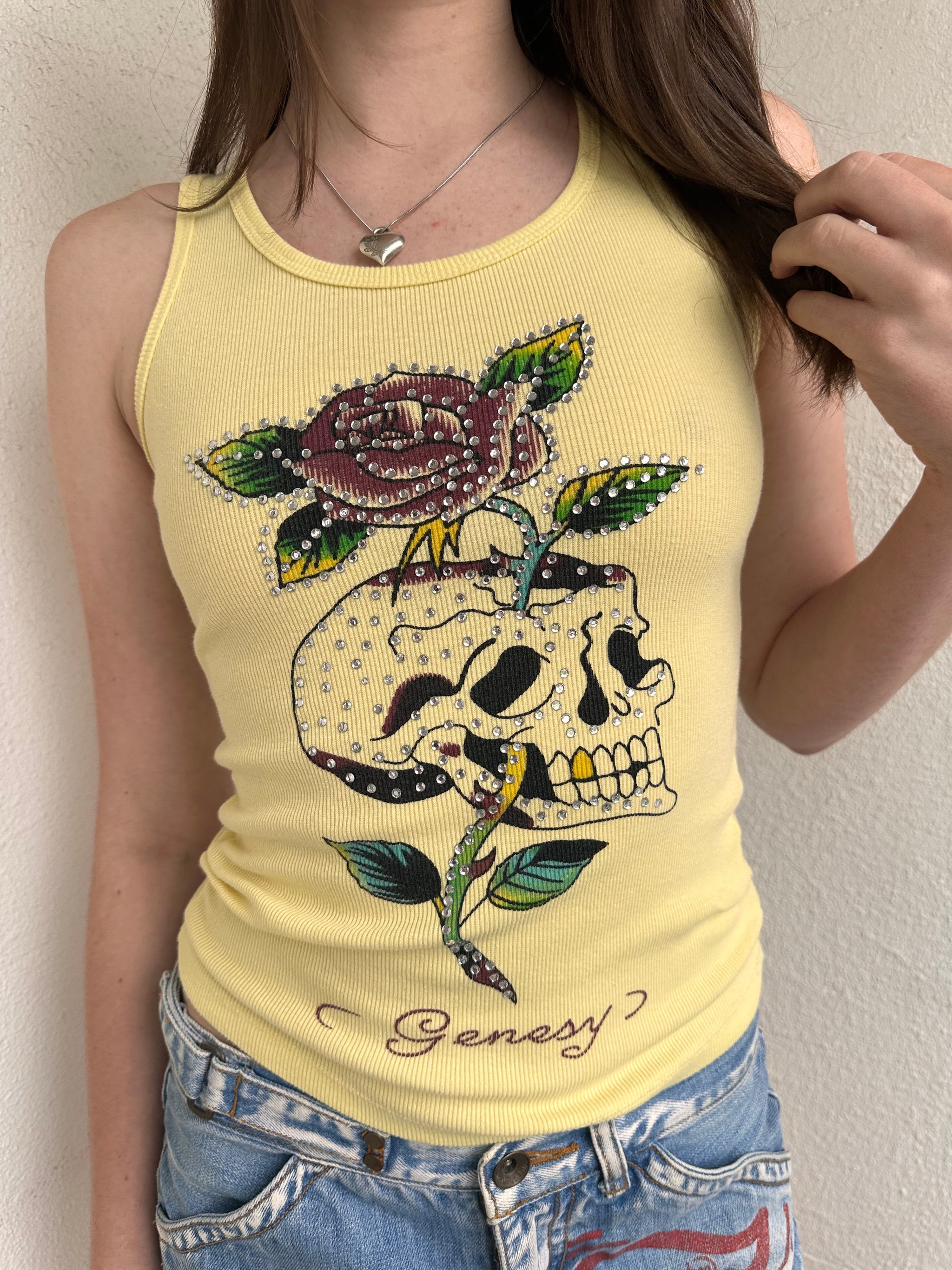 Women wearing a 00s Y2K Pastel yellow Y2K graphic tank from Genesy featuring a skull and flower print with rhinestone accents. 