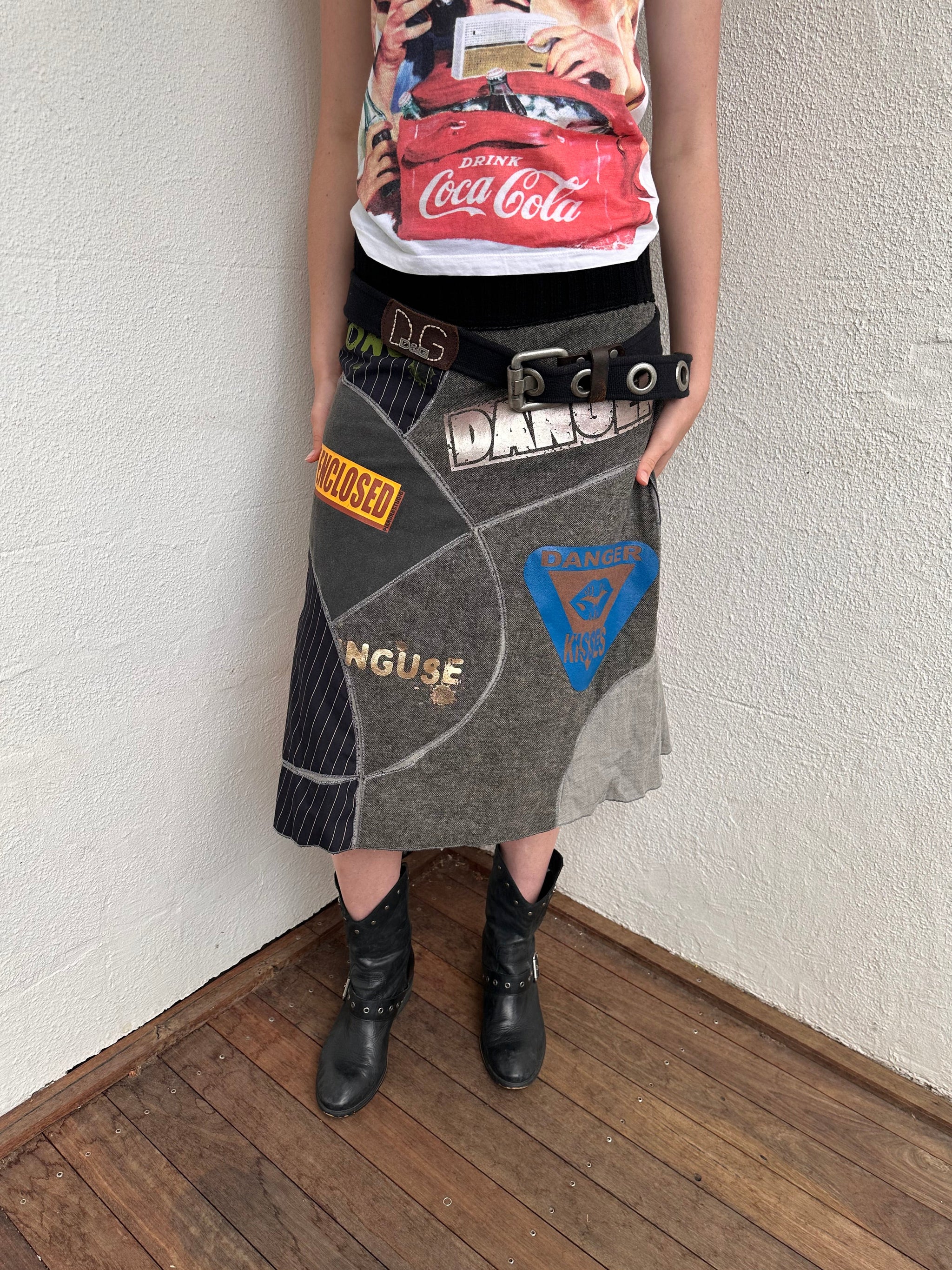Woman wearing a Y2K 00s grey patchwork midi skirt featuring a bold, multi-coloured print design.

